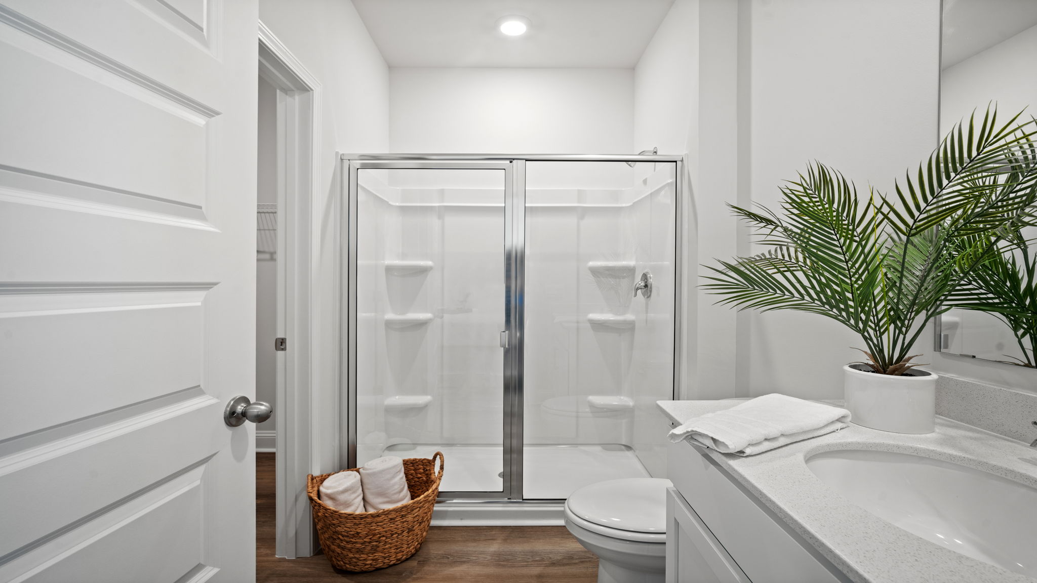 Primary bathroom with tile walk in shower, bright light fixtures, and with built in shelves. connecting walk-in closet.