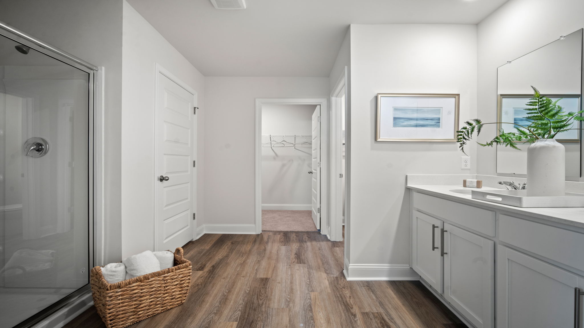 A modern bathroom featuring a double sink vanity with granite countertops and with spacious walk in closet and shower with built in shelves.