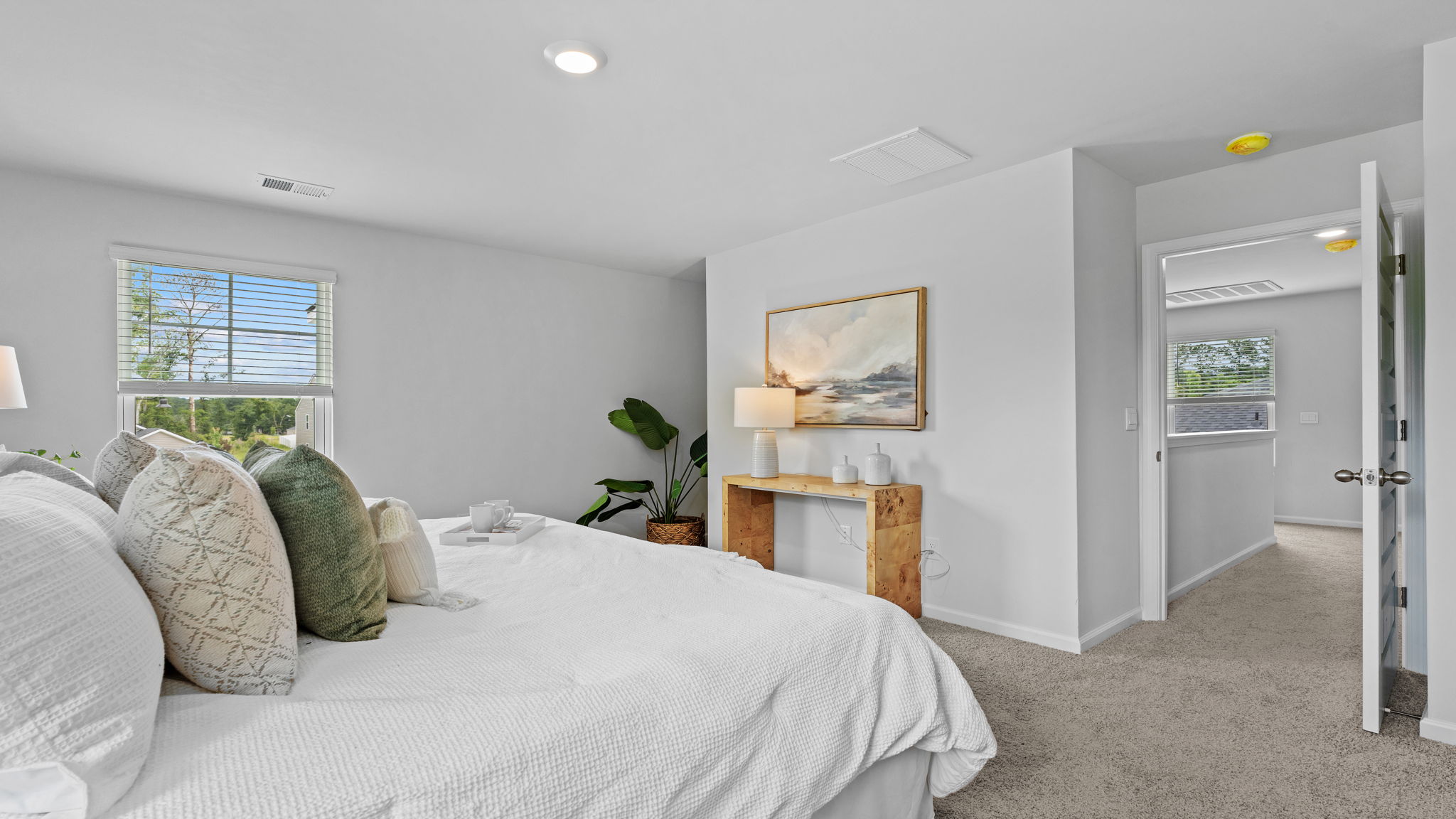 Spacious primary bedroom in the Downing floor plan showcasing elegant finishes, large windows, and convenient access to a luxurious en-suite bathroom.