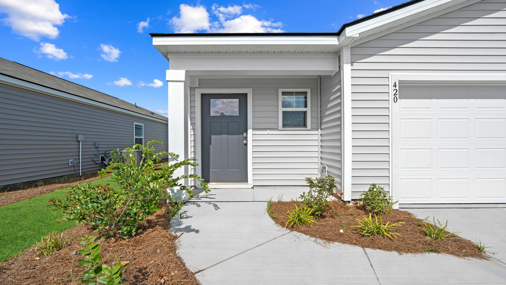 Willow floor plan exterior in Rice Hope by D.R. Horton featuring attractive curb appeal, covered entryway, landscaped front yard, and modern coastal-inspired home design.