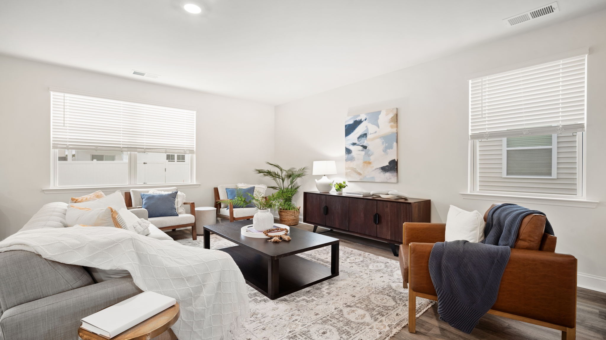 Spacious living room in the Belhaven by D.R. Horton featuring large windows, abundant natural light, modern finishes, and a welcoming open-concept design.