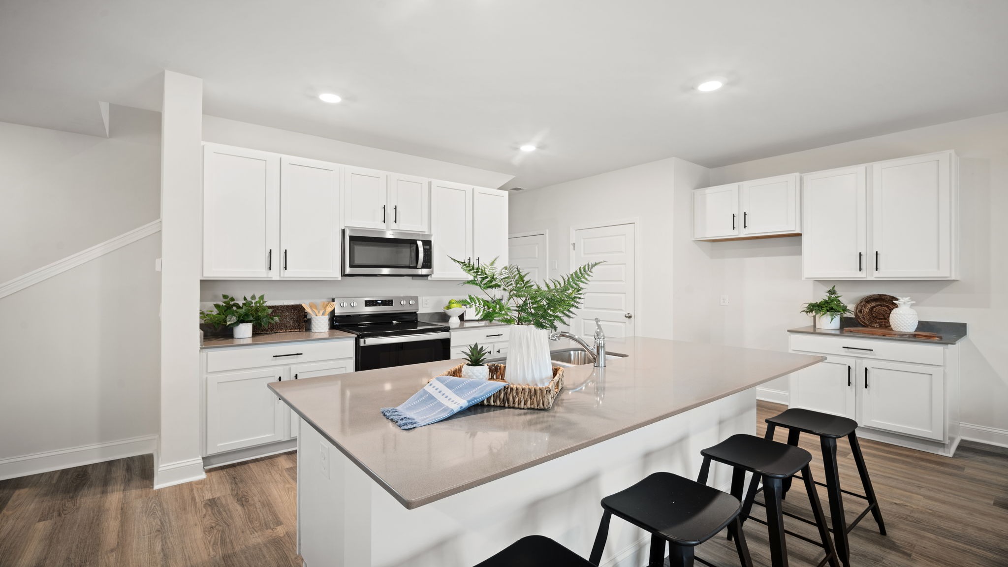 Open-concept kitchen with oversized island in the Belhaven floorplan featuring natural light, energy-efficient appliances, stylish fixtures, and functional space for everyday living.