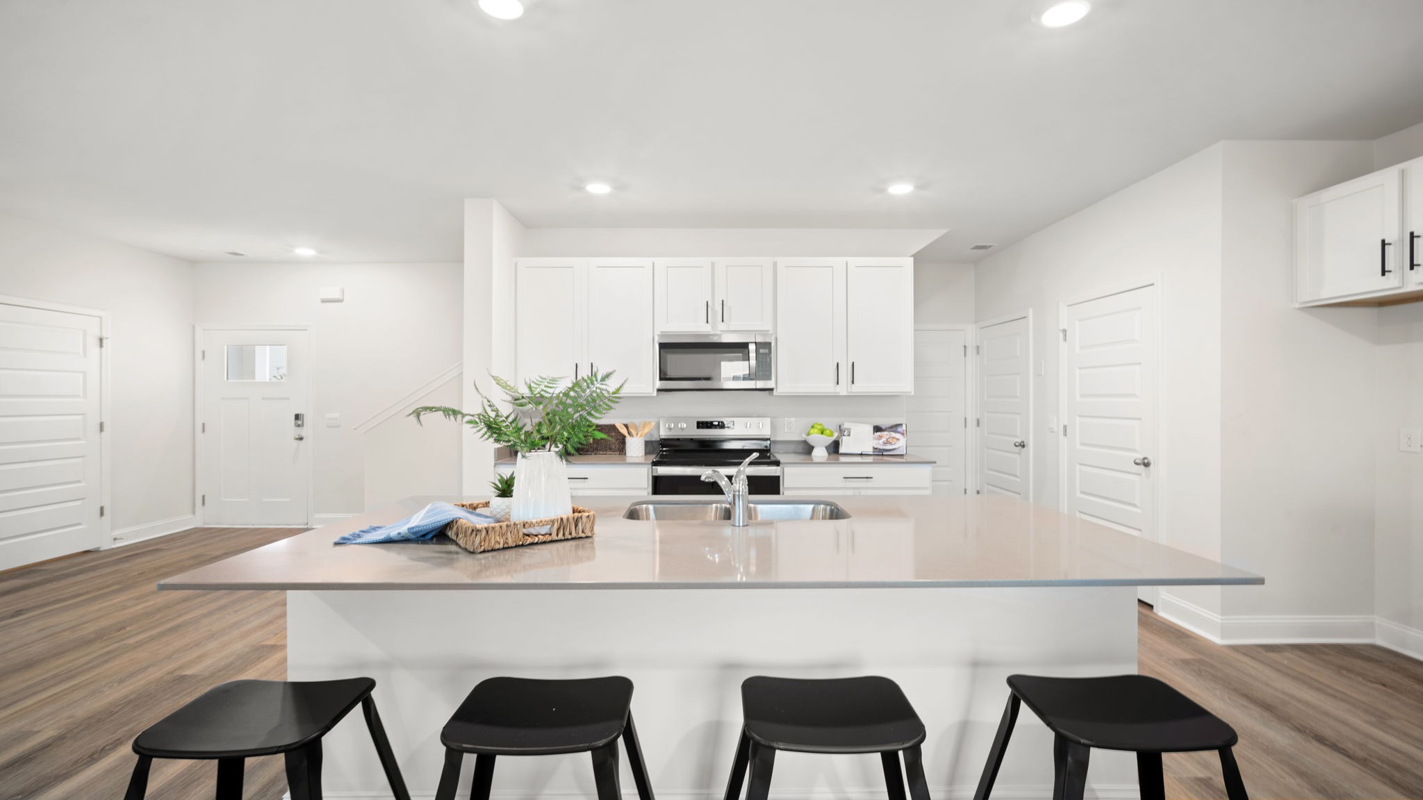 Modern kitchen in the Belhaven floorplan by D.R. Horton featuring a spacious center island, stainless steel appliances, designer cabinetry, and an open-concept layout ideal for cooking and entertaining.