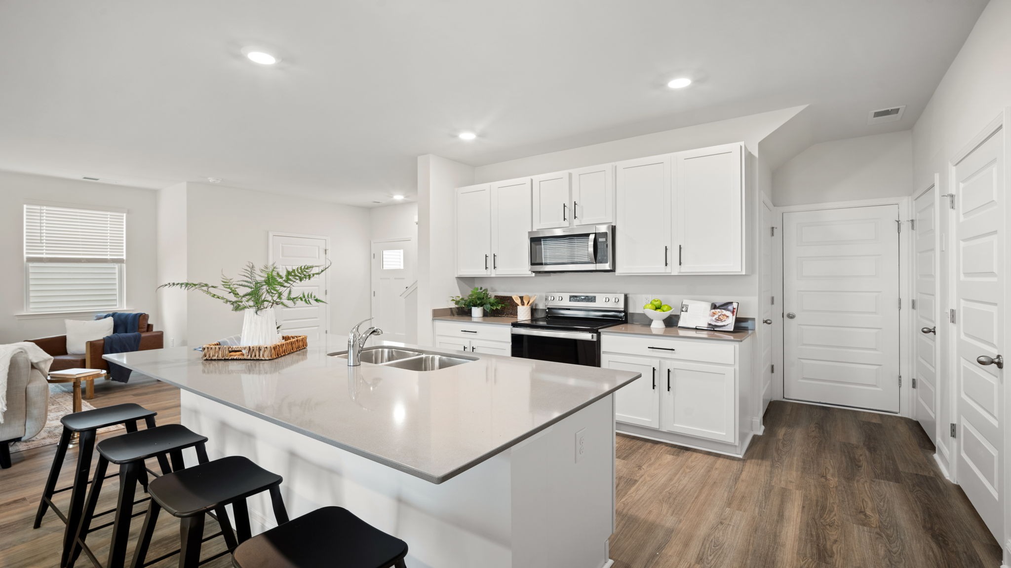 Bright kitchen in the Belhaven by D.R. Horton showcasing abundant cabinet storage, expansive countertops, contemporary finishes, and seamless flow into the dining and living areas.