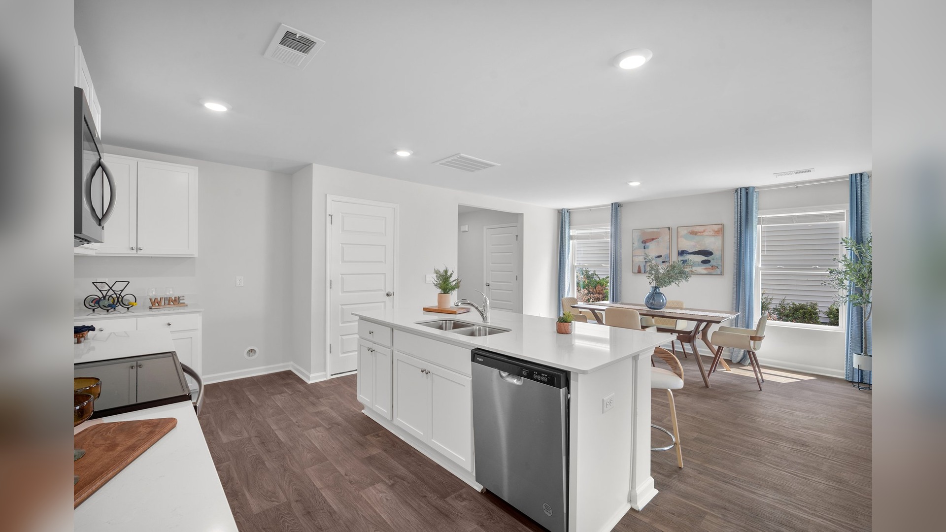 Kitchen with a view of the island with a stainless dishwasher and the dining area in the background