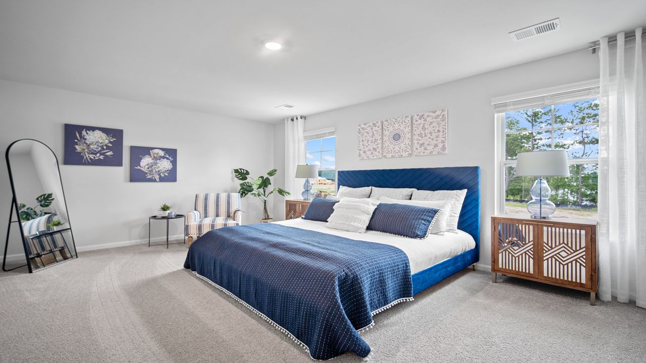 Primary bedroom decorated with a bed, side table and a mirror