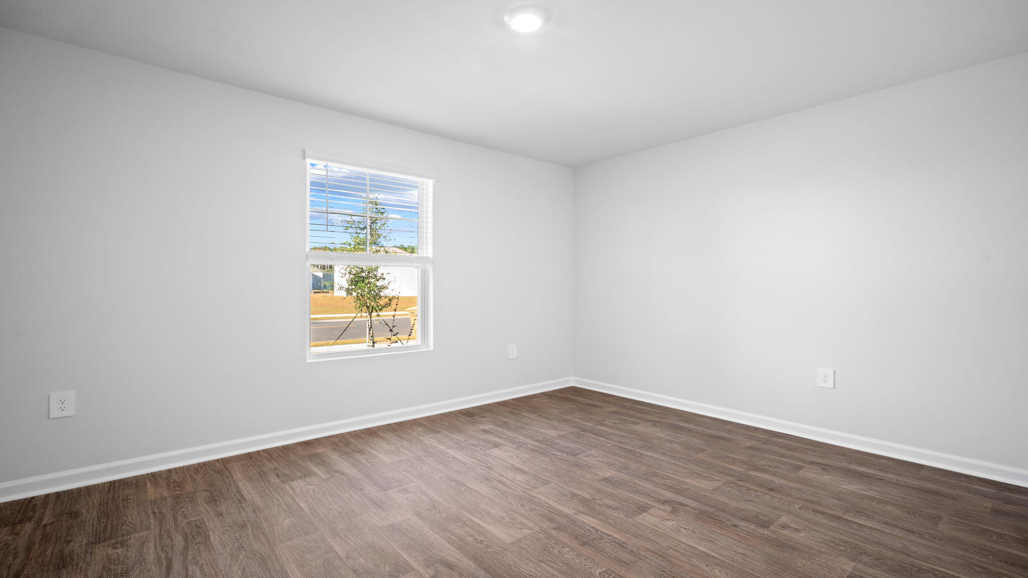 Bedroom with hardwood floors and large single window for natural light.