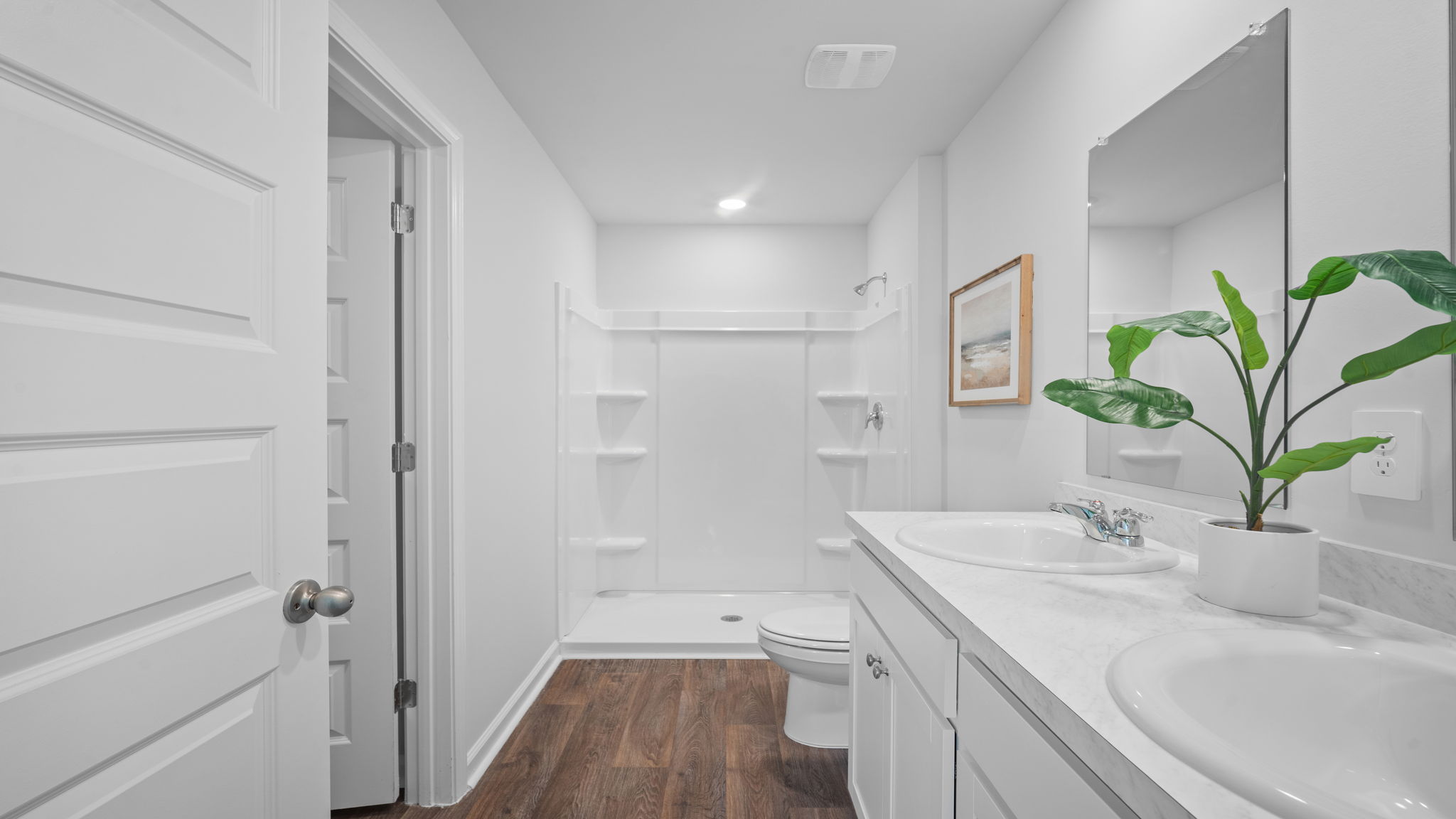 A modern bathroom featuring a double sink vanity with granite countertops and with spacious walk in closet and shower with built in shelves.
