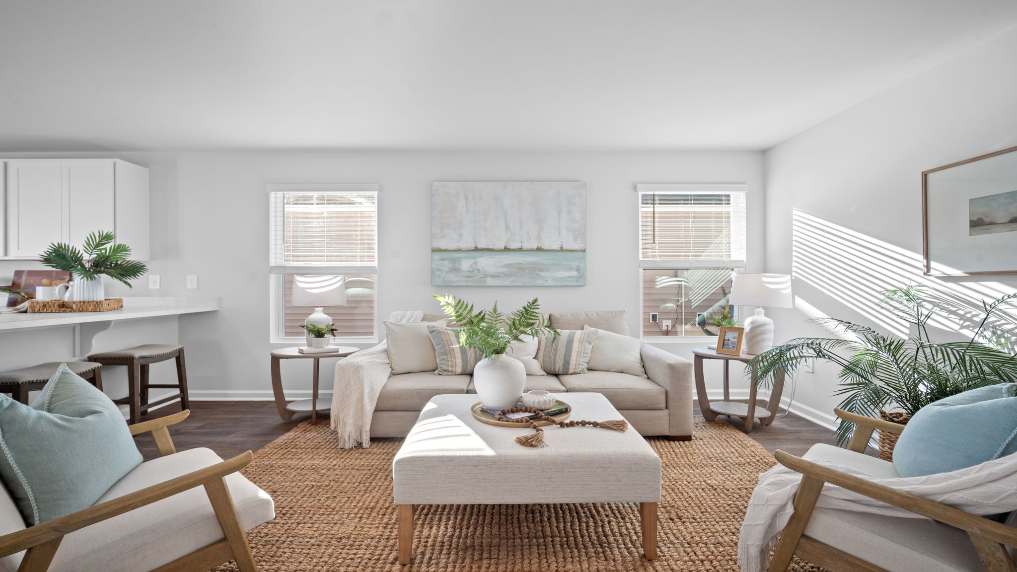 Bright living room in the Lewis floor plan at Rice Hope by D.R. Horton featuring large windows, abundant natural light, luxury flooring, and an open-concept design that creates a warm and welcoming atmosphere.