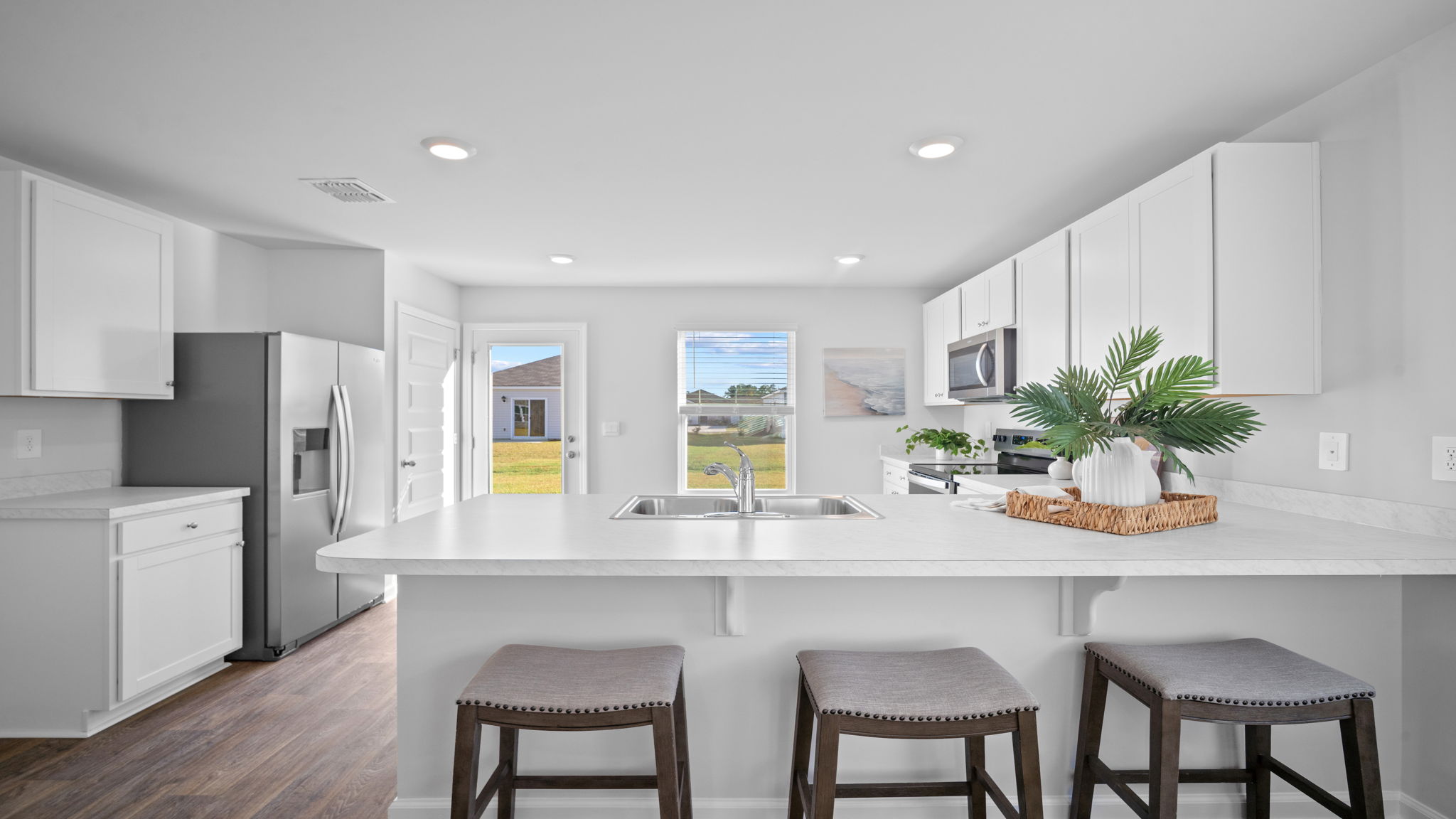Designer kitchen in the Lewis floor plan at Rice Hope by D.R. Horton featuring granite countertops, stainless steel appliances, modern cabinetry, a spacious center island with seating, and an open-concept layout designed for entertaining and everyday living.