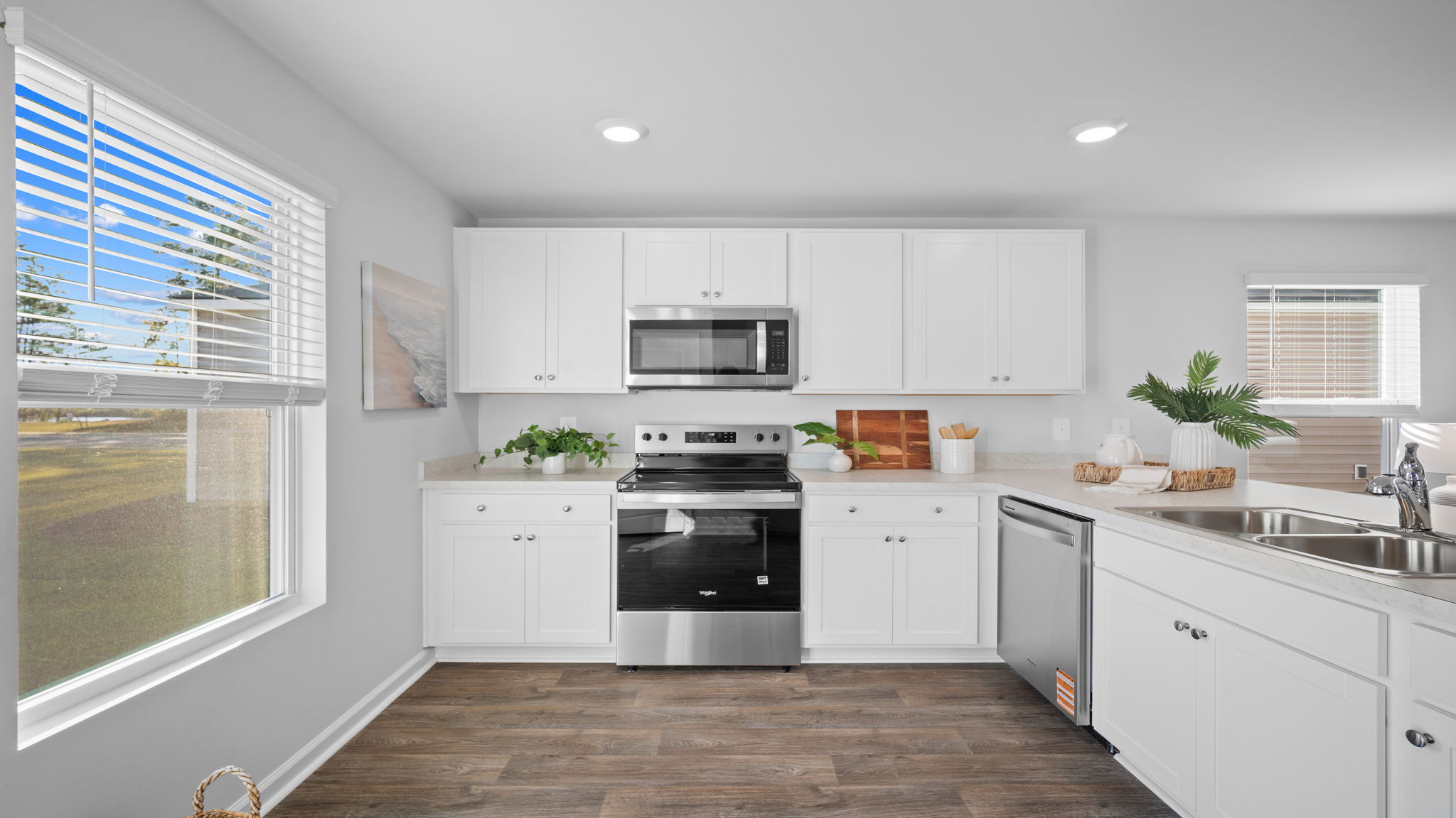 Modern kitchen in the Lewis floor plan by D.R. Horton in Rice Hope showcasing abundant cabinet storage, sleek finishes, a large center island, and seamless flow to the dining and living areas.