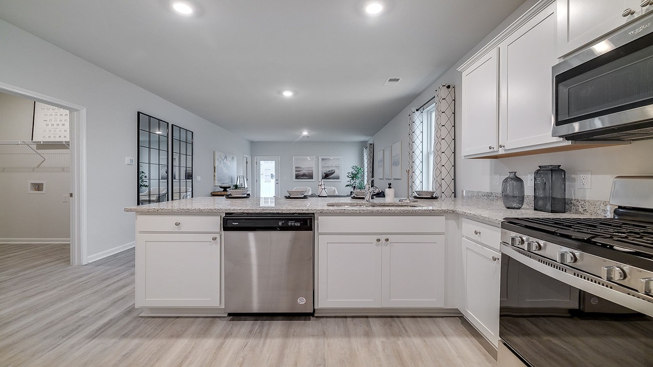 Modern kitchen in the Helena floor plan at Rice Hope by D.R. Horton featuring granite countertops, stainless steel appliances, upgraded cabinetry, a large center island, and an open-concept layout designed for entertaining and everyday living.