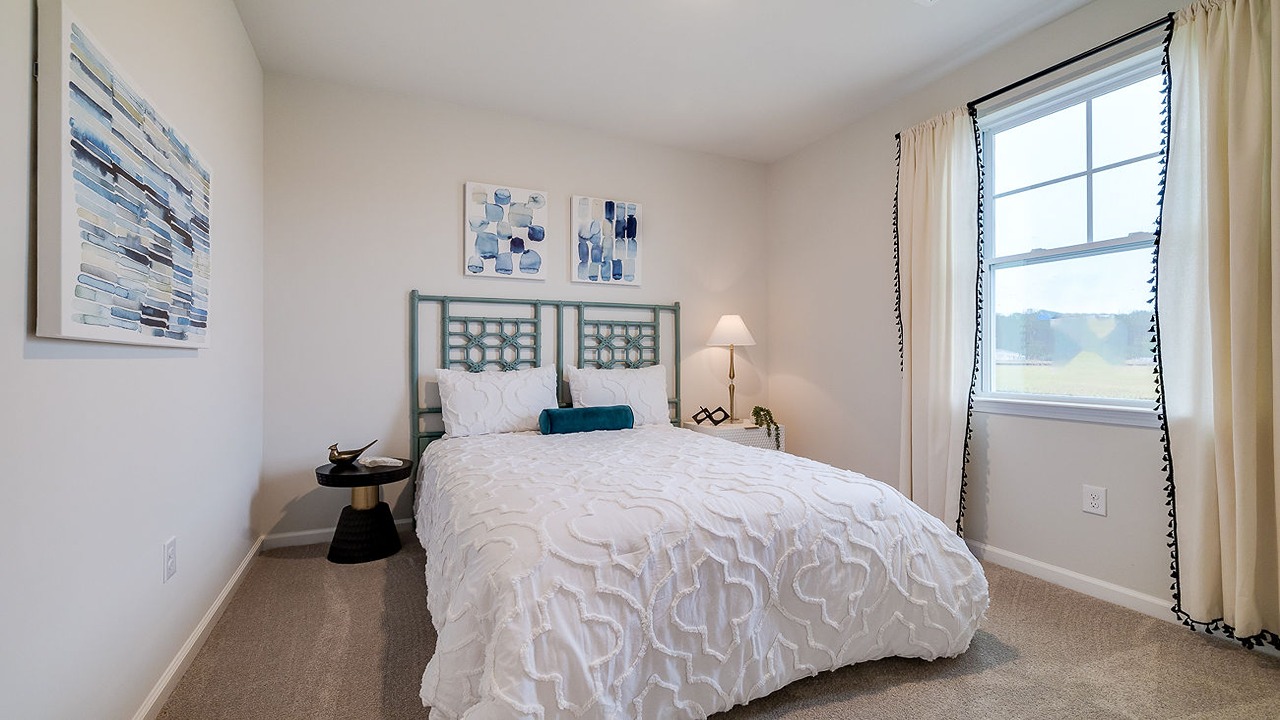 Comfortable guest bedroom in the Helena floor plan at Rice Hope by D.R. Horton featuring abundant natural light, spacious closet storage, modern finishes, and a versatile layout ideal for guests, family members, or a home office.