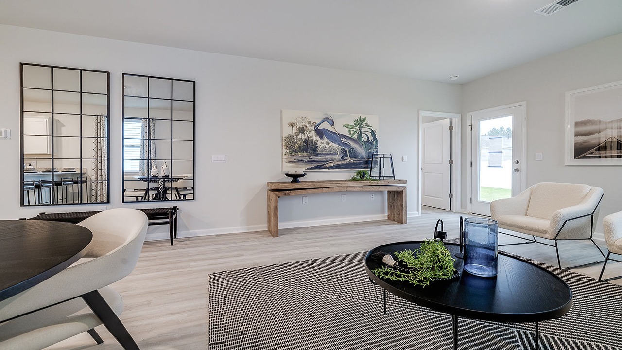 Inviting family room in the Helena floor plan showcasing luxury flooring, bright natural lighting, and seamless connection to the kitchen and dining area for modern living.