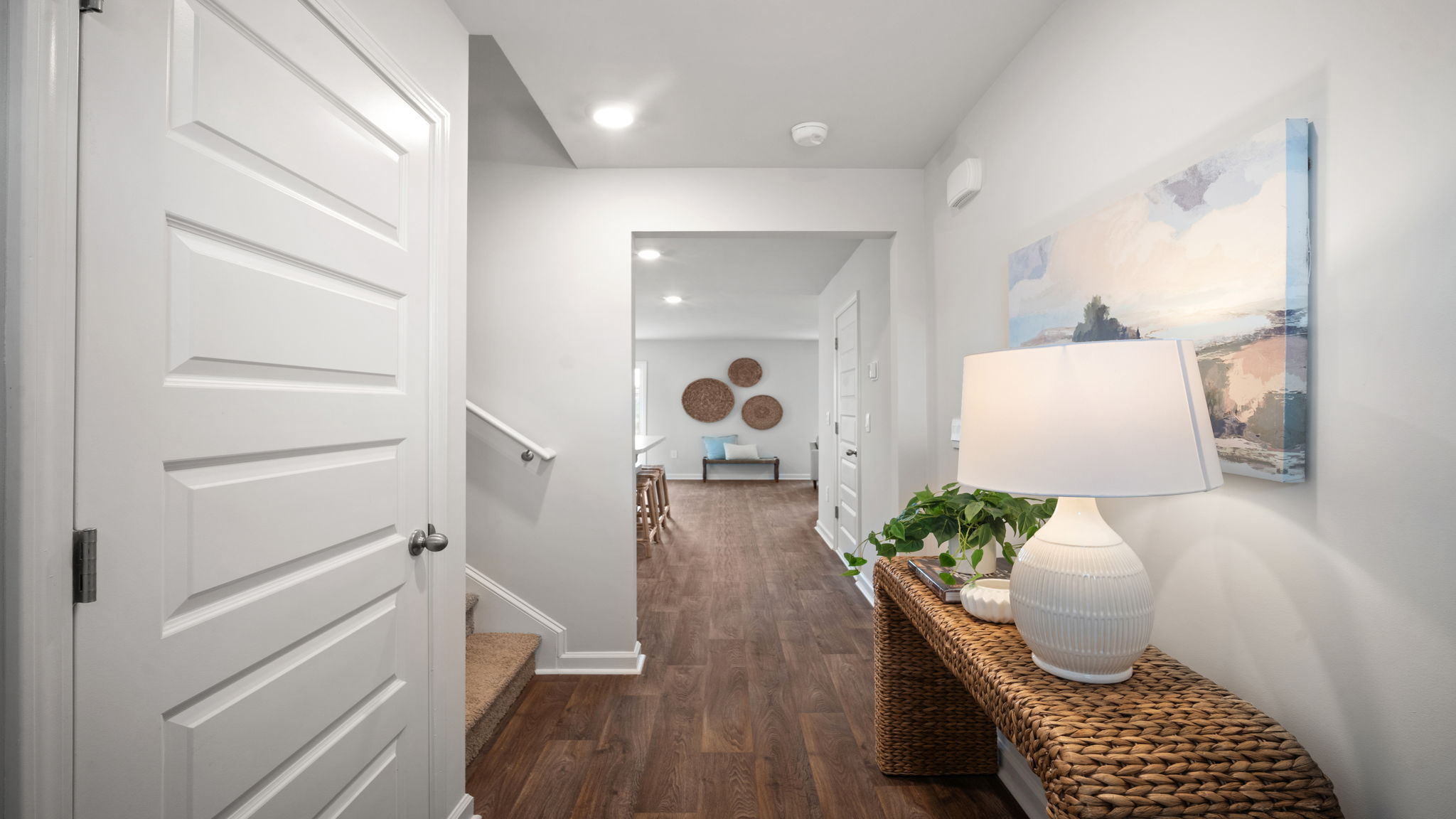 Front entryway and foyer with hardwood floors and  hall leading into the kitchen and living area.