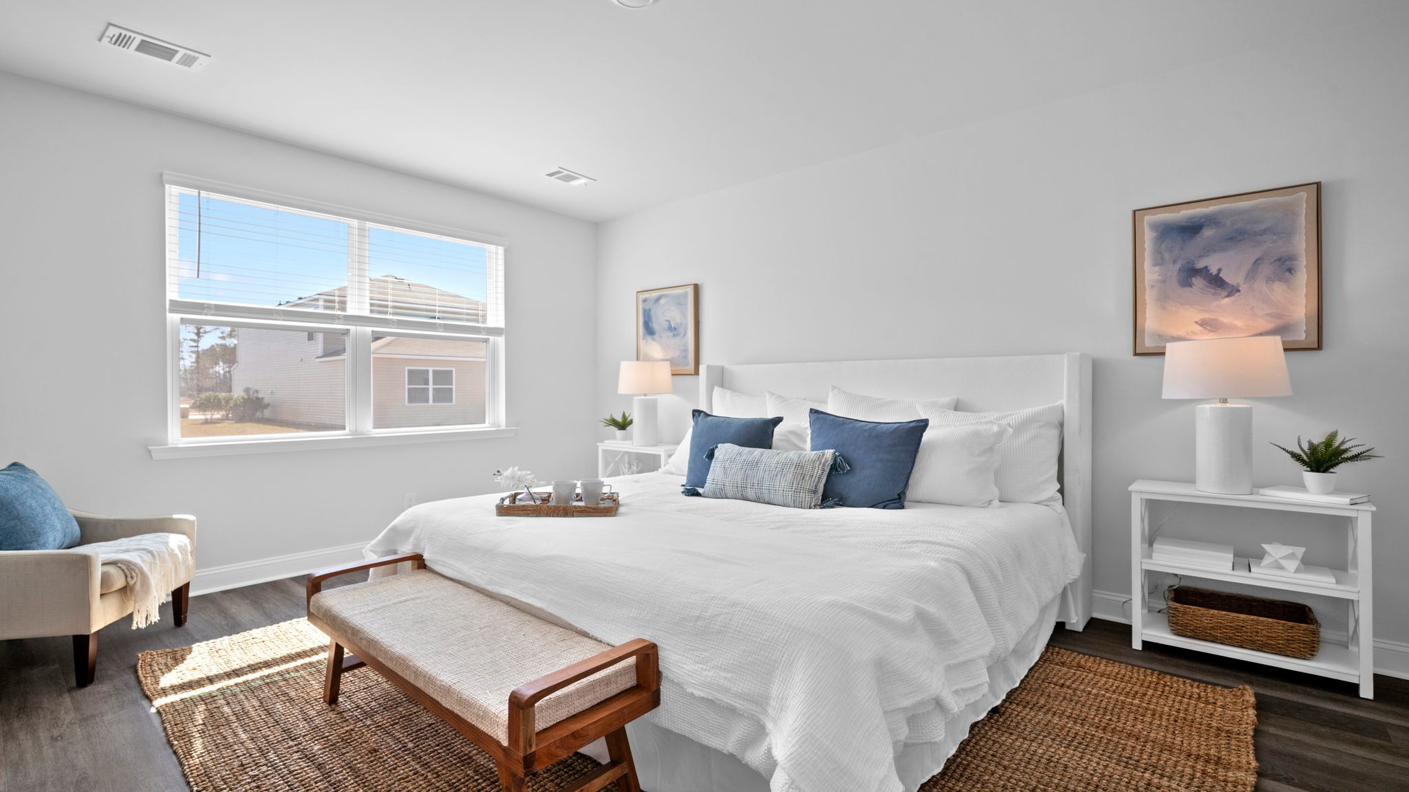 Primary bedroom decorated with a bed, side table, bench and a chair
