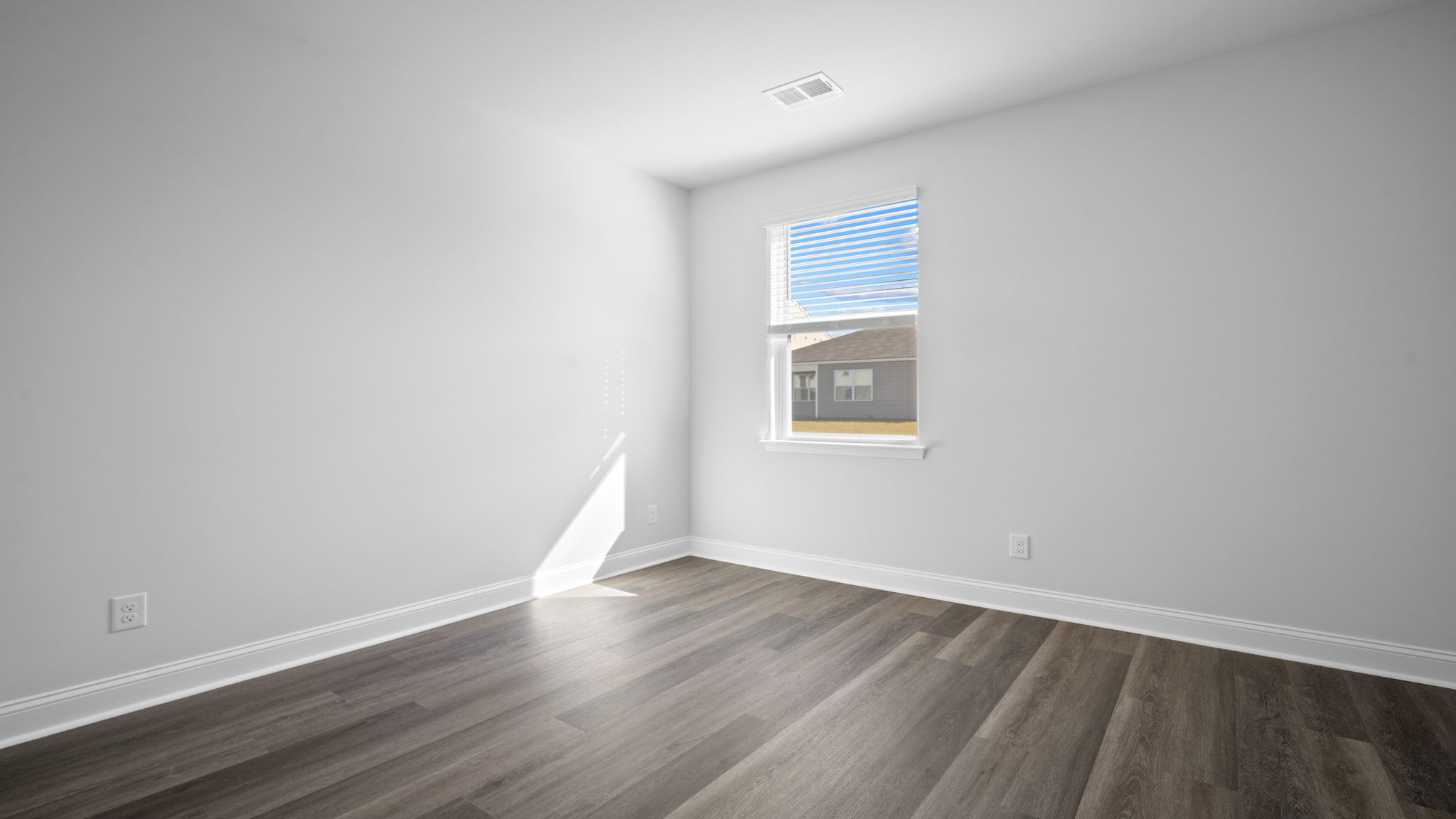 Bedroom with hardwood floors and large single window for natural light.