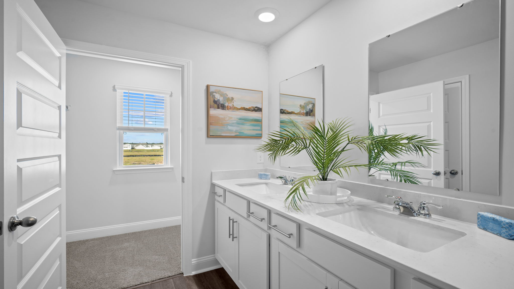 Primary bathroom featuring a double sink vanity with granite countertops and with spacious walk in closet and shower with built in shelves.