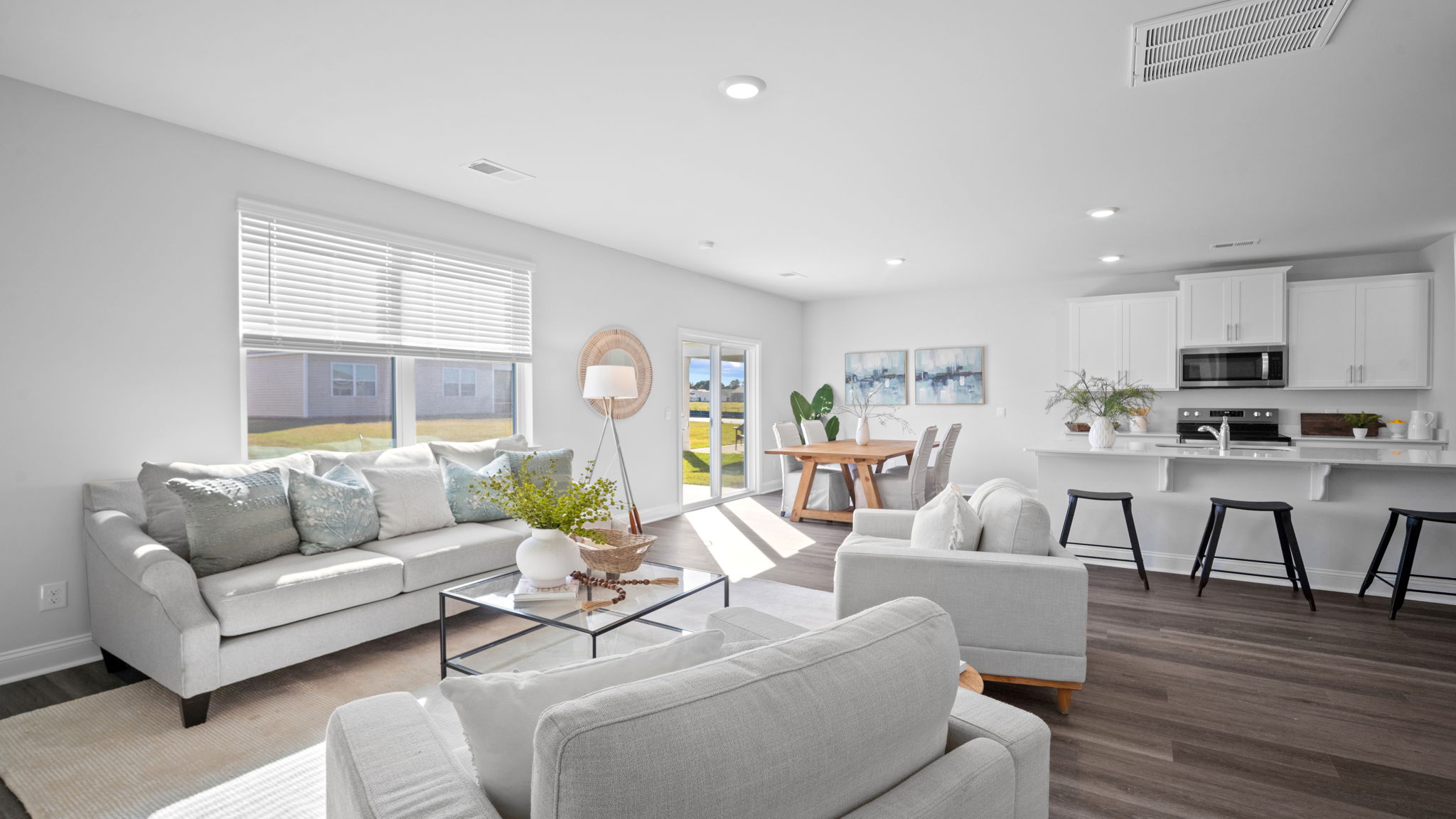 A spacious open floor plan living room and kitchen area with hardwood floors, and trey ceilings.