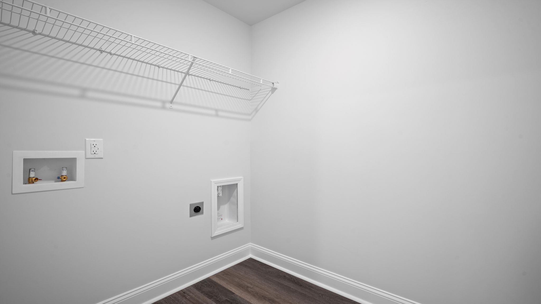 Spacious laundry area has room for a washer and dryer with built in shelves.