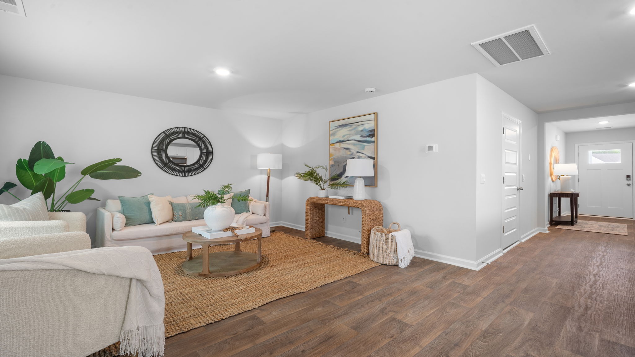 Living room decorated with a couch, chairs and tables with a view back to the front of the home