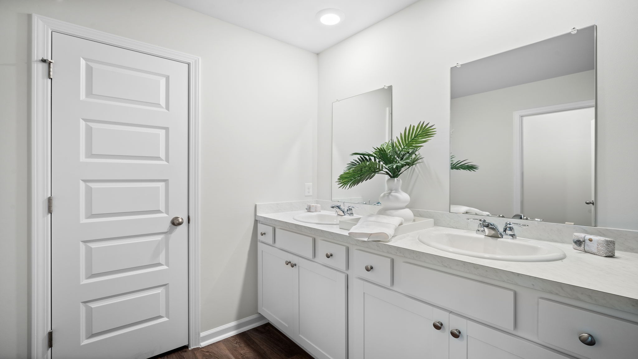 A modern bathroom featuring a double sink vanity with granite countertops and with spacious walk in closet and shower with built in shelves.