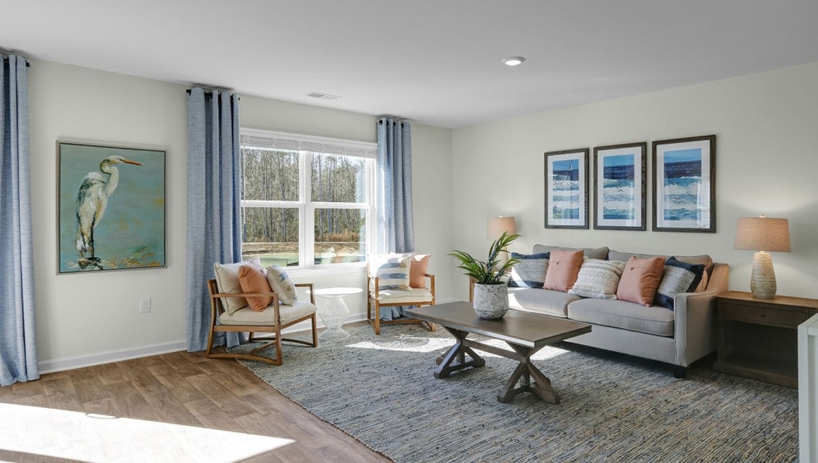 "Open living room in the Macon floor plan by D.R. Horton featuring abundant natural light, spacious seating areas, and modern design."