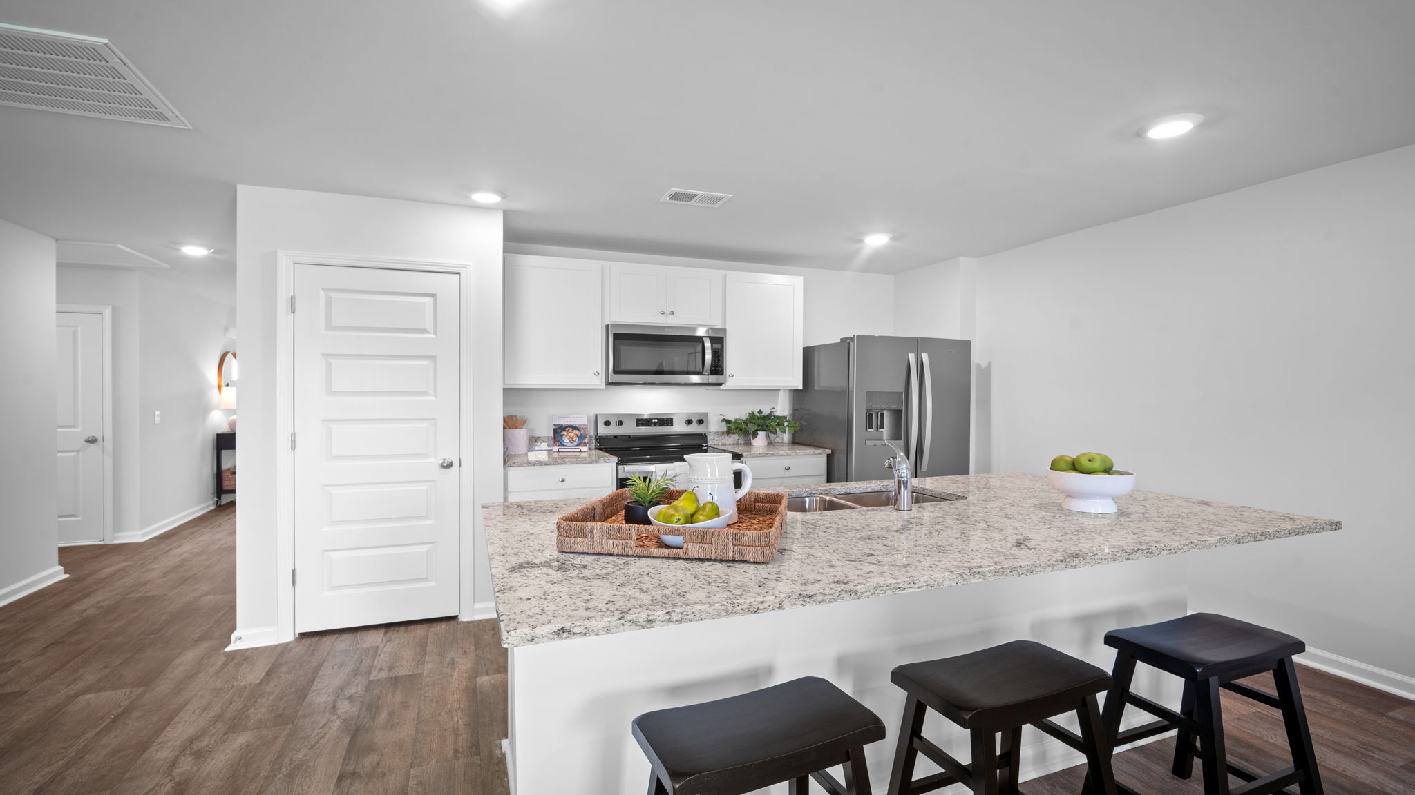 Gourmet kitchen in the Freeport by D.R. Horton featuring oversized center island, granite countertops, stainless steel appliances, and modern cabinetry.
