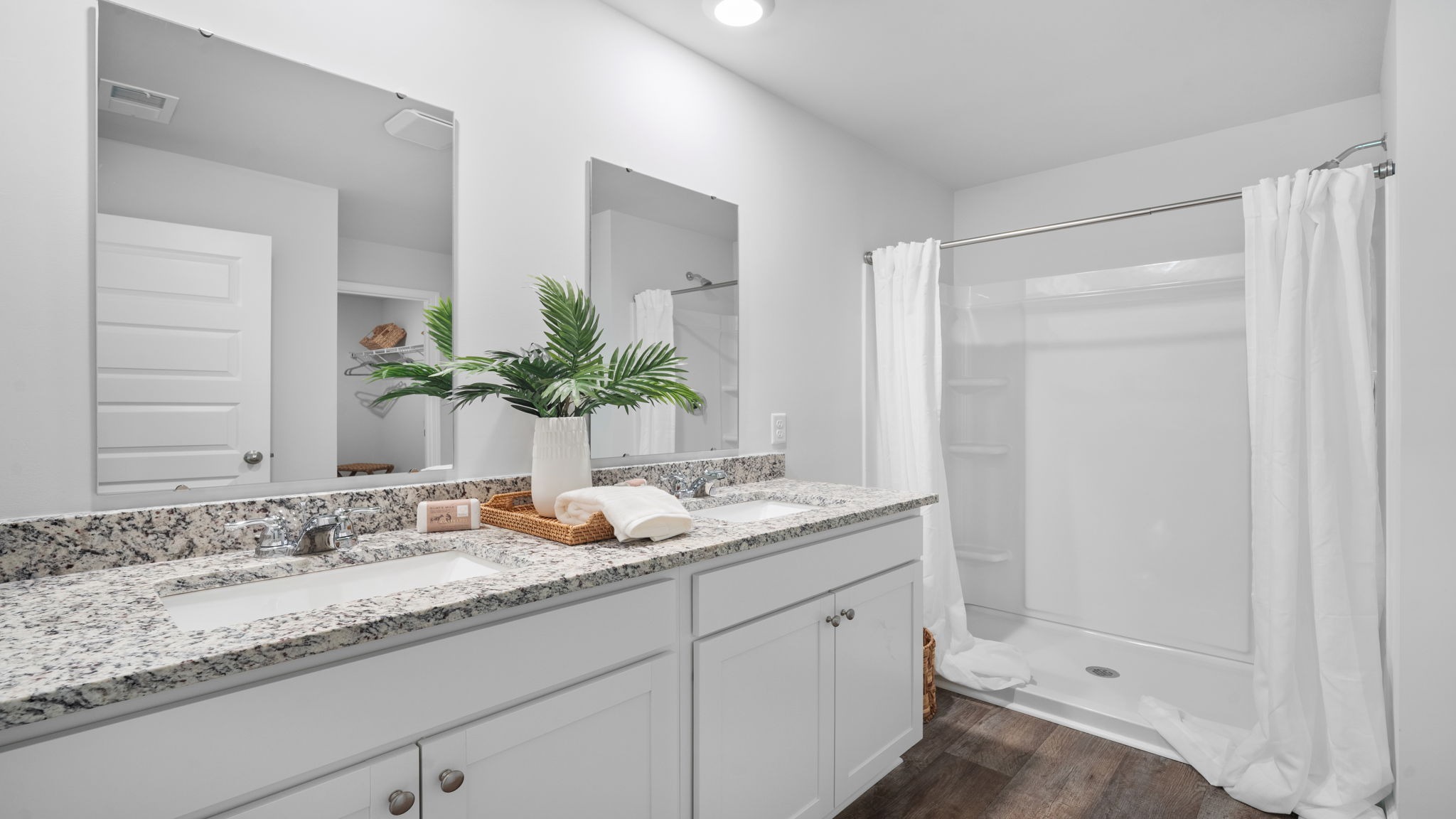 Primary bathroom with double vanities and a stand-up shower