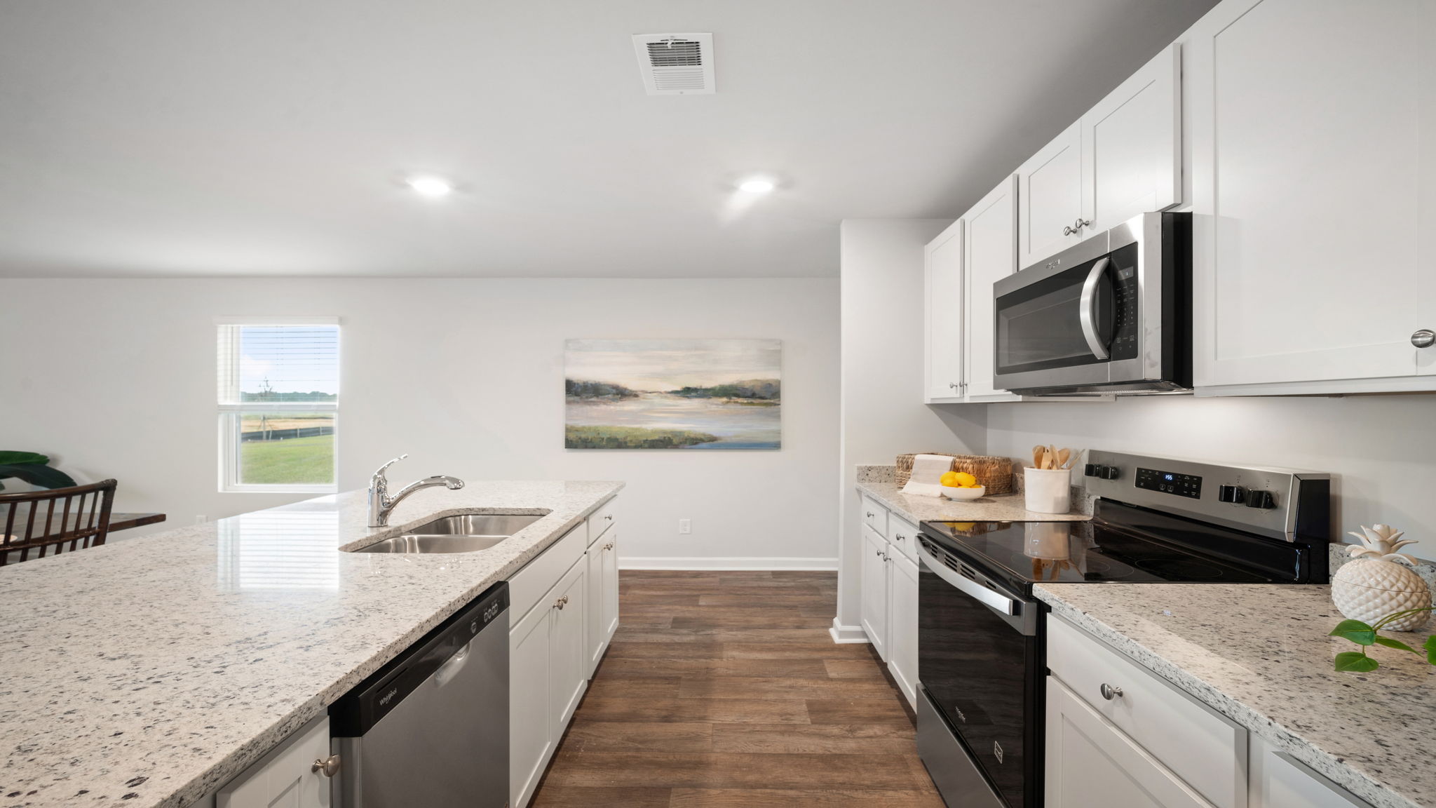Kitchen walkway with counters on both sides and a stainless dishwasher in the island
