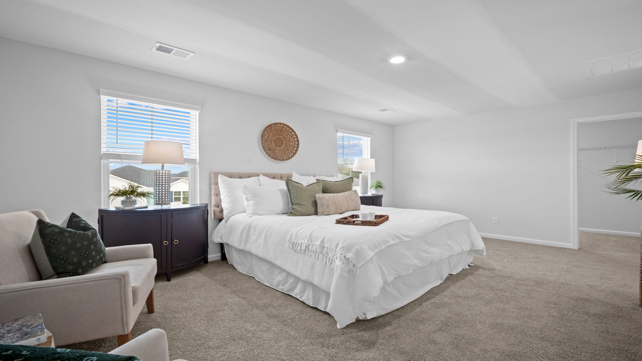 Primary bedroom with carpeted floors, large windows, and trey ceilings.