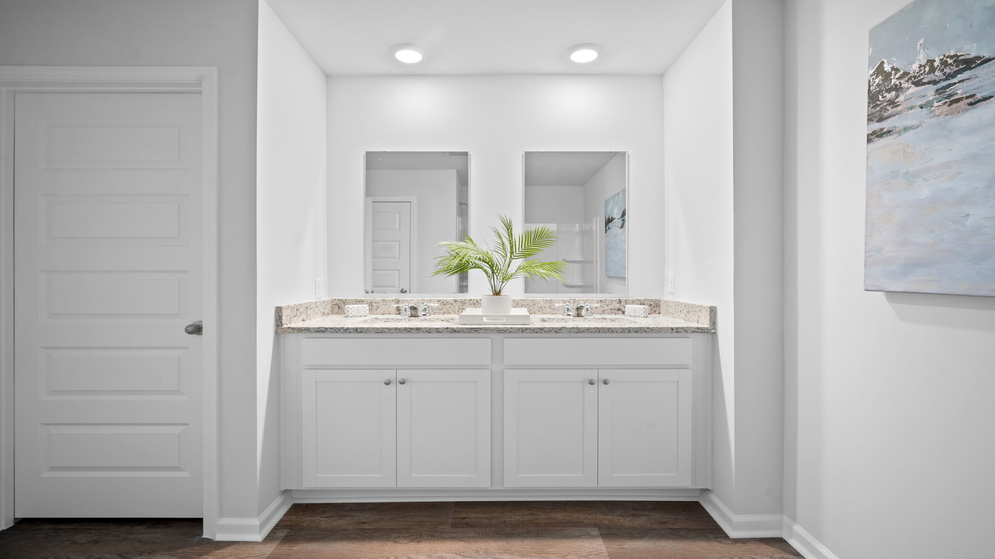 Primary bathroom featuring a double sink vanity with granite countertops and with spacious walk in closet and shower with built in shelves.