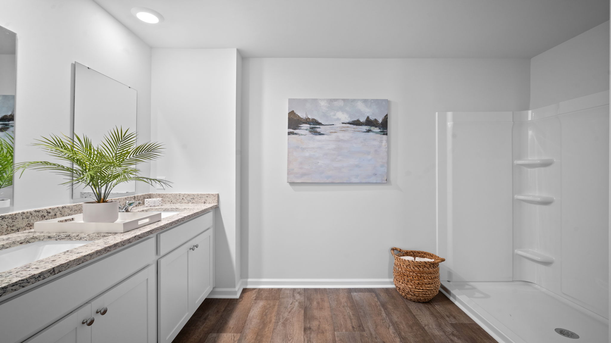 A modern bathroom featuring a double sink vanity with granite countertops and with spacious walk in closet and shower with built in shelves.