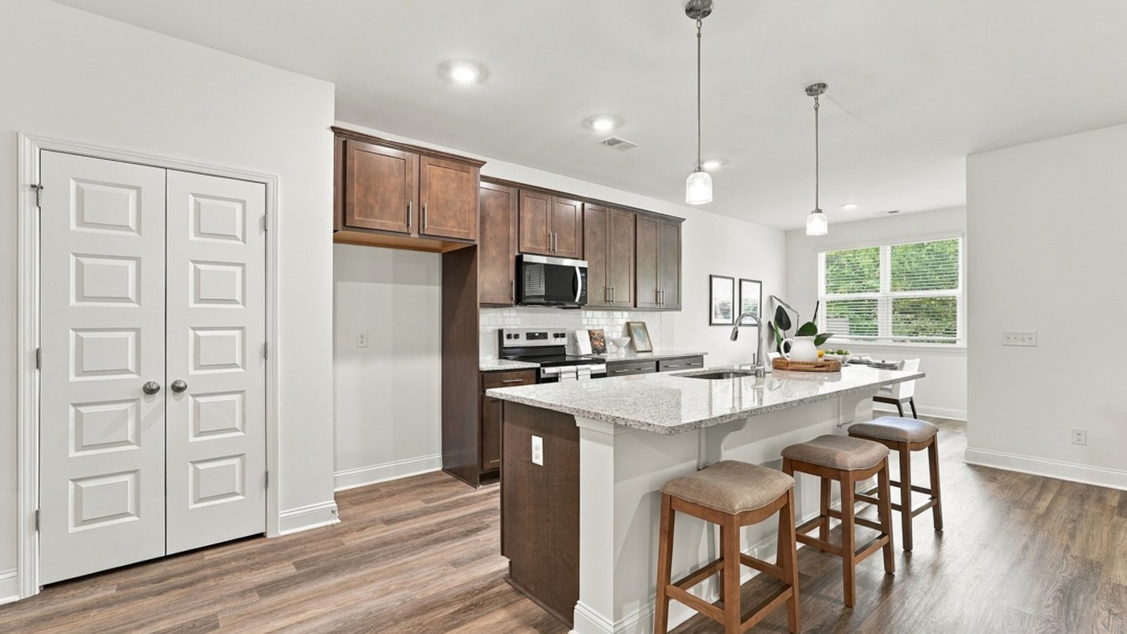 Modern kitchen with center island, granite countertops, designer cabinetry, and bar seating in a new construction home.