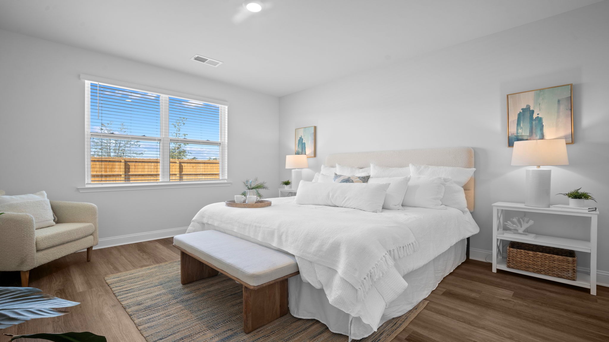 Primary bedroom decorated with a bed, bench, side table and seating