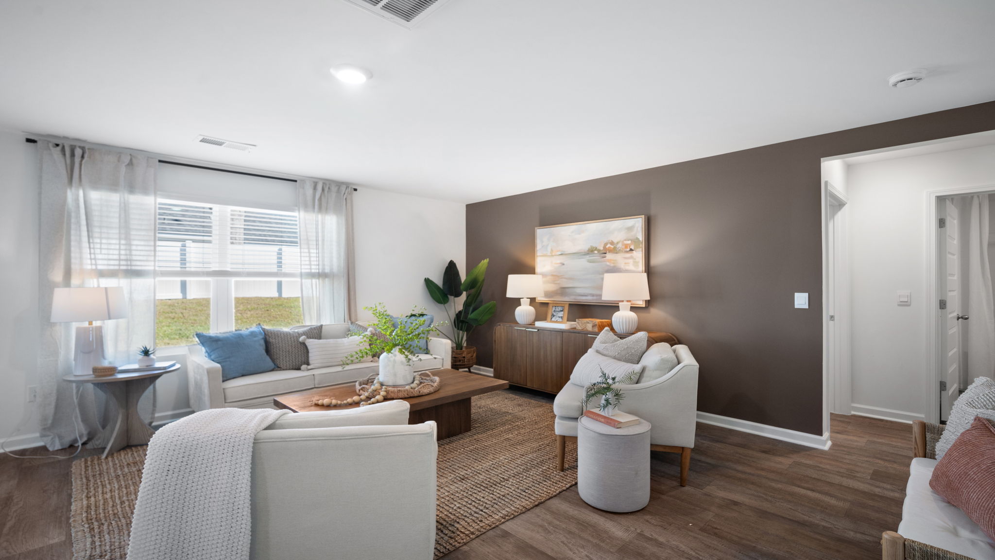 Bright family room in the Hayden floor plan by D.R. Horton showcasing large windows, modern finishes, and seamless connectivity to the kitchen and dining areas.