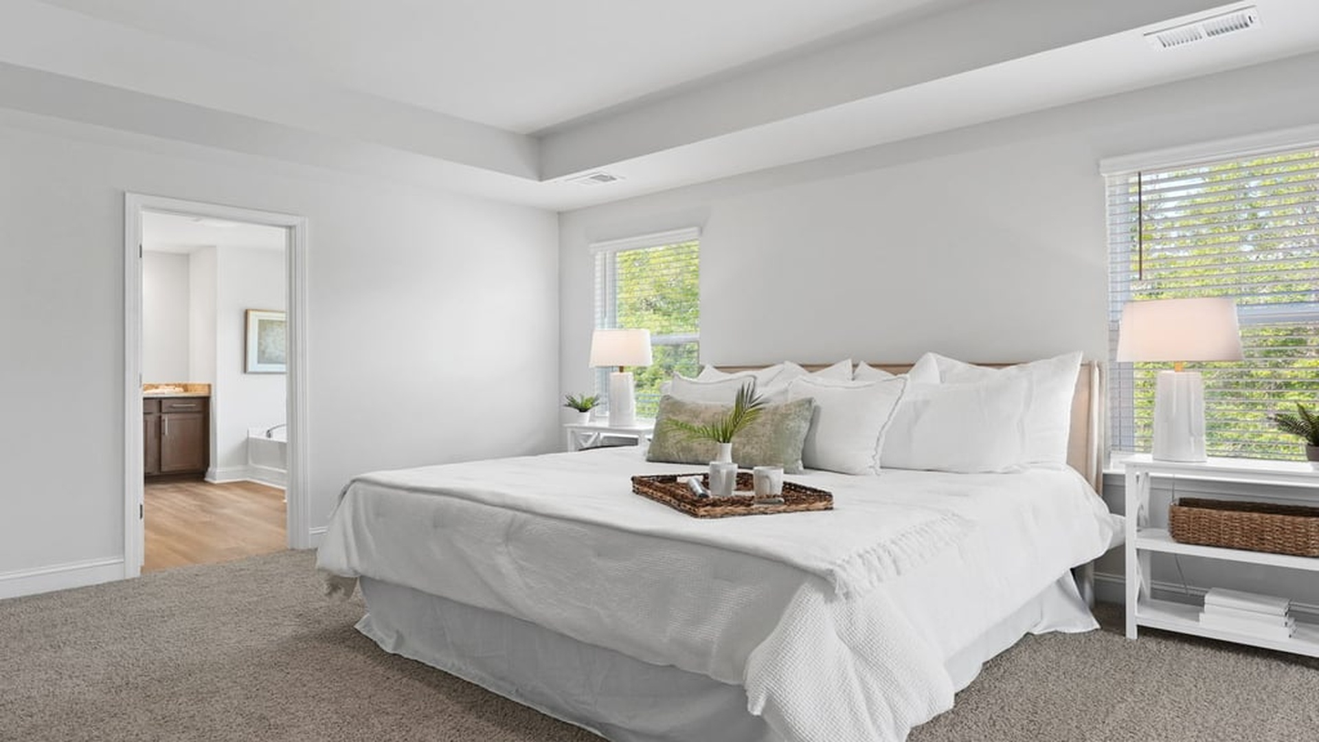 large primary bedroom with view of large primary bathroom brown cabinets