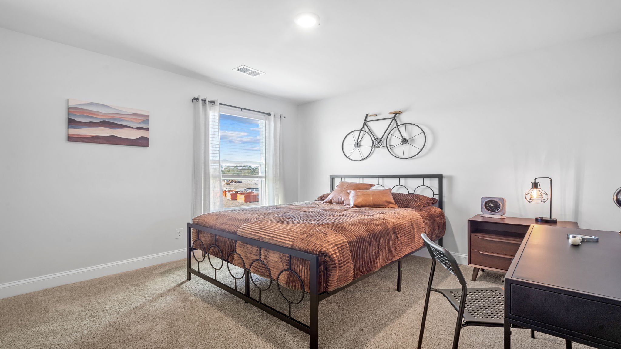 Bedroom with bed, nightstand, desk, and a bicycle picture