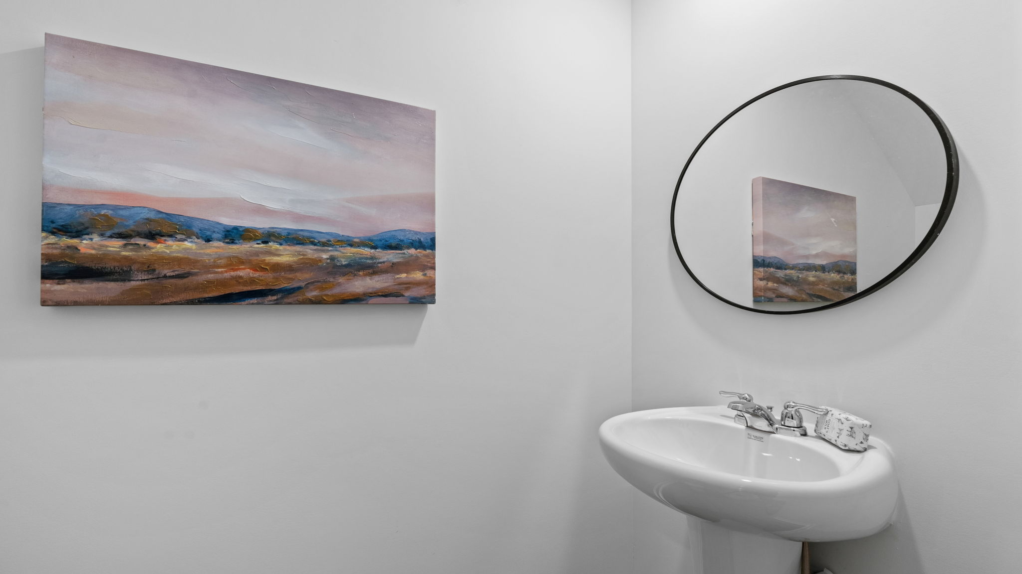 Half bathroom with contemporary finishes, wall artwork, and stylish round mirror in the Darwin floorplan.
