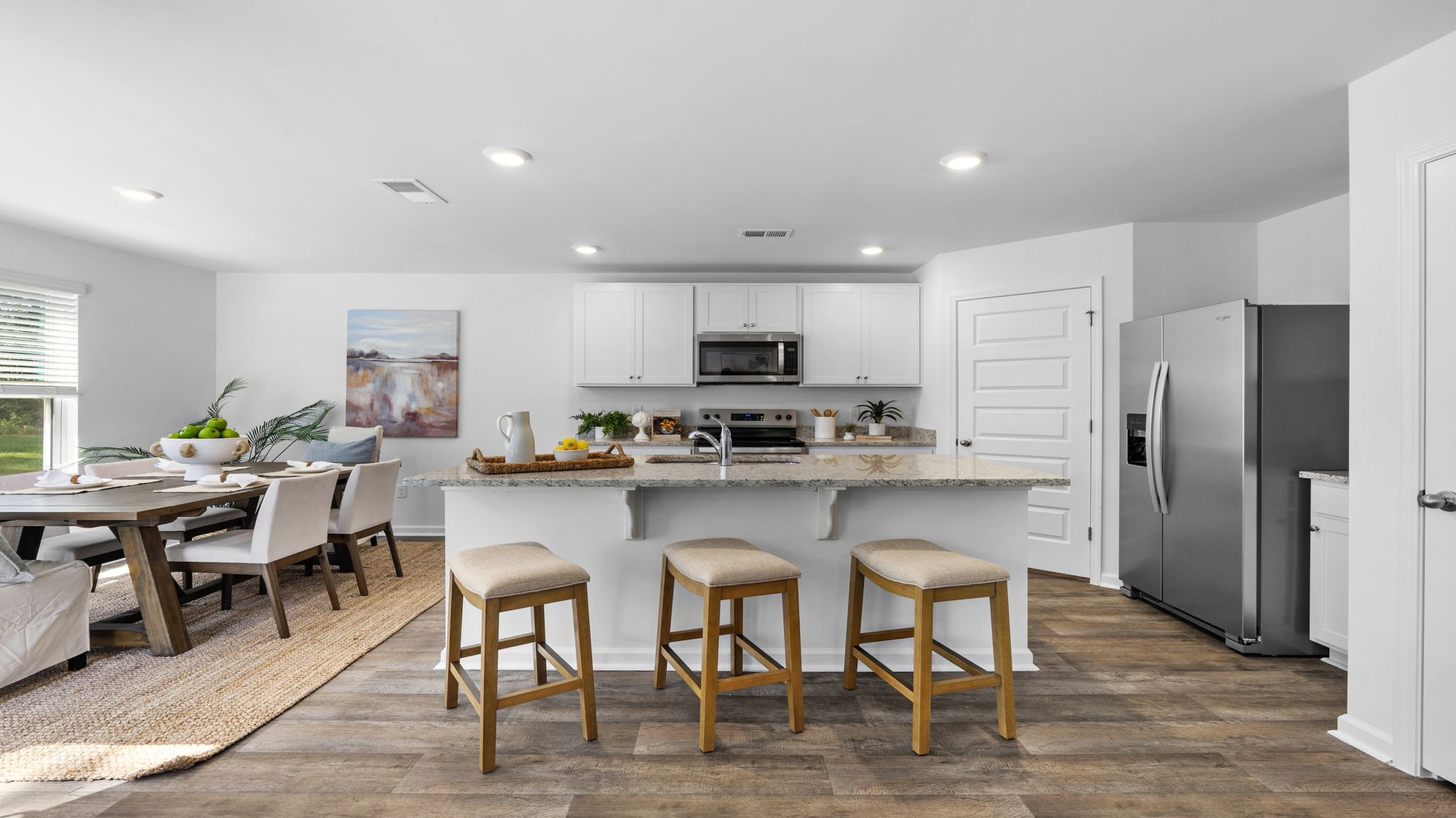 Open kitchen and dining area featuring a large island, stainless steel appliances, and ample cabinetry
