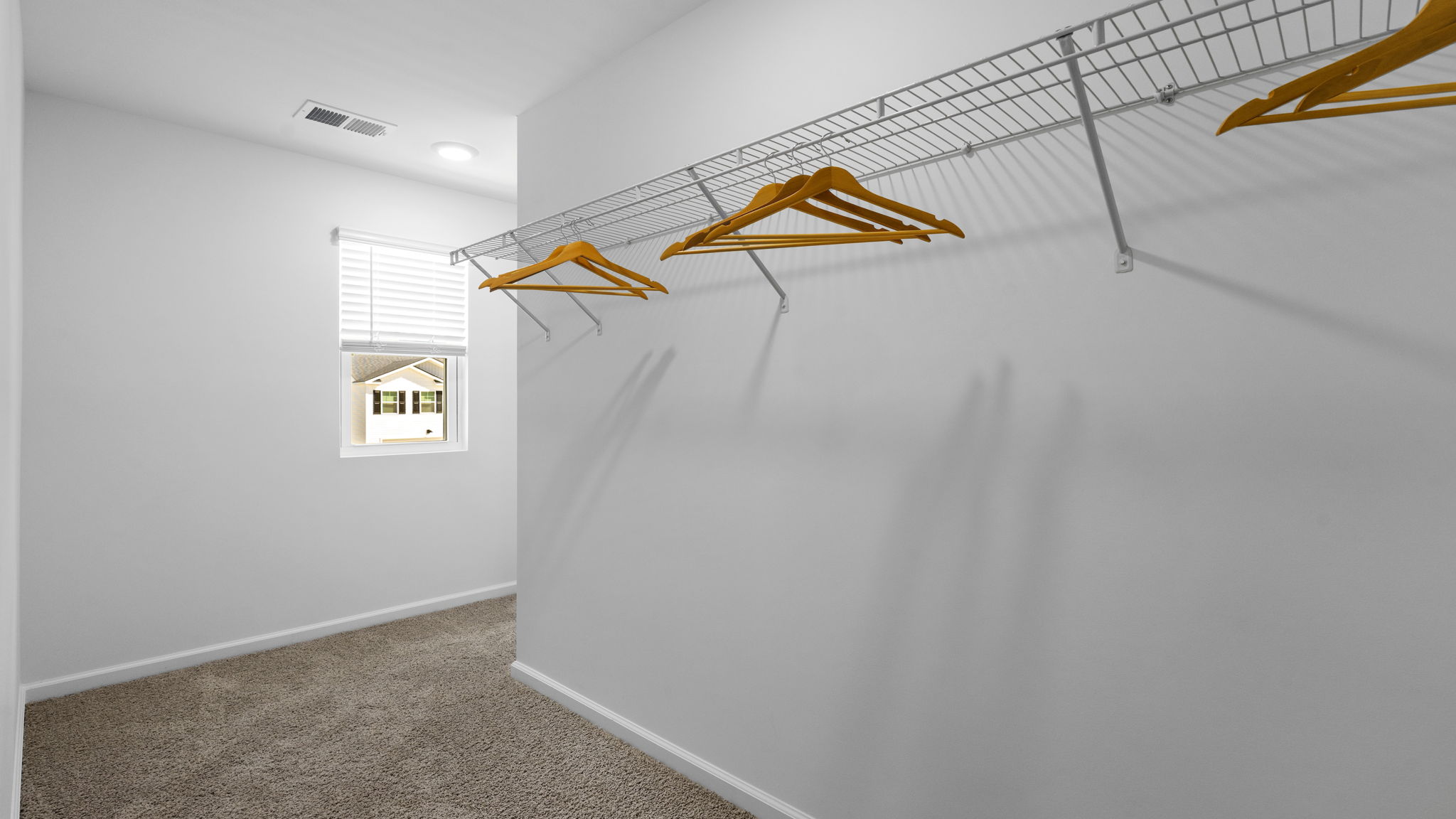 Spacious walk-in closet in the owner's suite with built-in shelving and hanging storage.