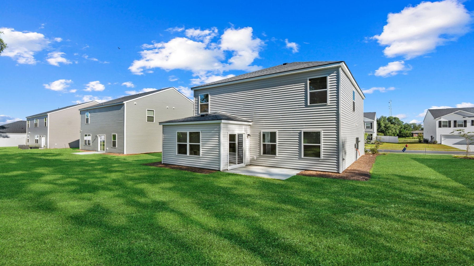 Side and rear exterior view of the Darwin floorplan showing backyard space, covered patio, and neighboring homes.