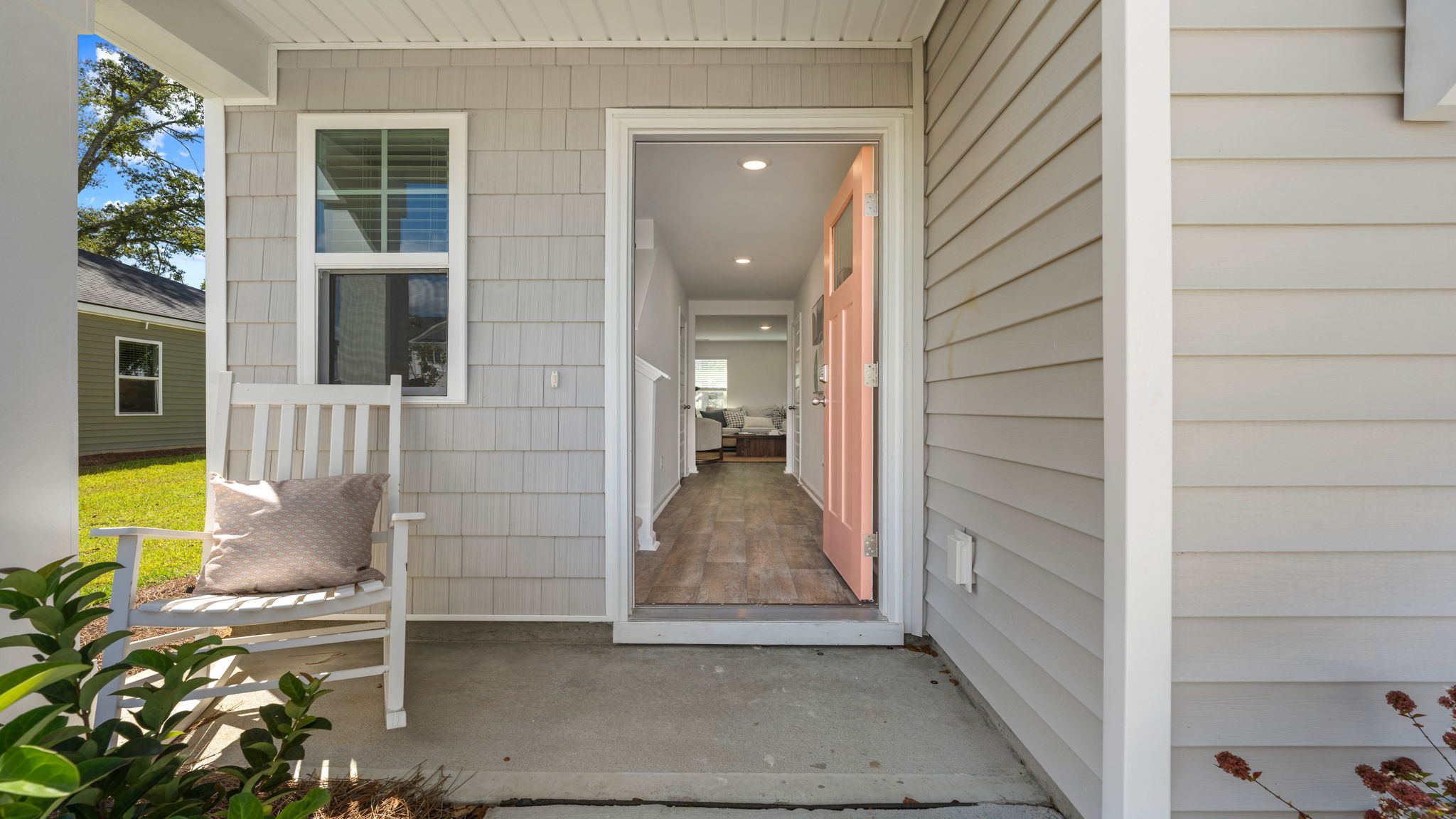 covered front entry of the Darwin floorplan with welcoming porch, decorative landscaping, and glass front door.