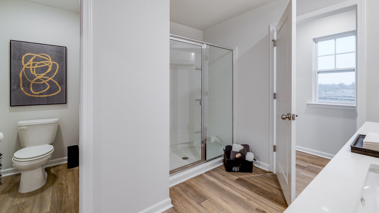 Primary bathroom in Hayden model featuring dual vanities and modern finishes with walk-in closet access.