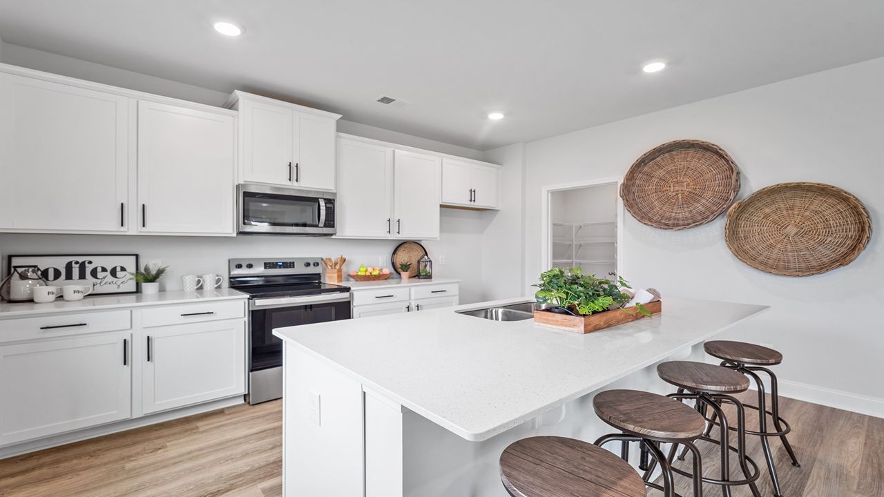 Gourmet kitchen featuring oversized island, stainless steel appliances, walk-in pantry, and abundant cabinetry.