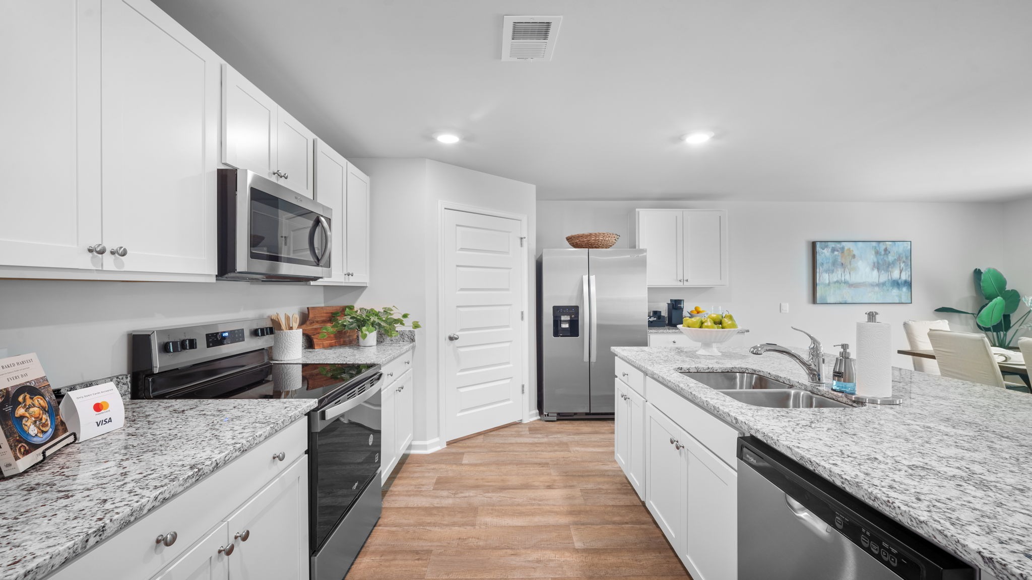 Modern kitchen in the Cali floor plan featuring a large center island, granite countertops, stainless steel appliances, and open-concept design.