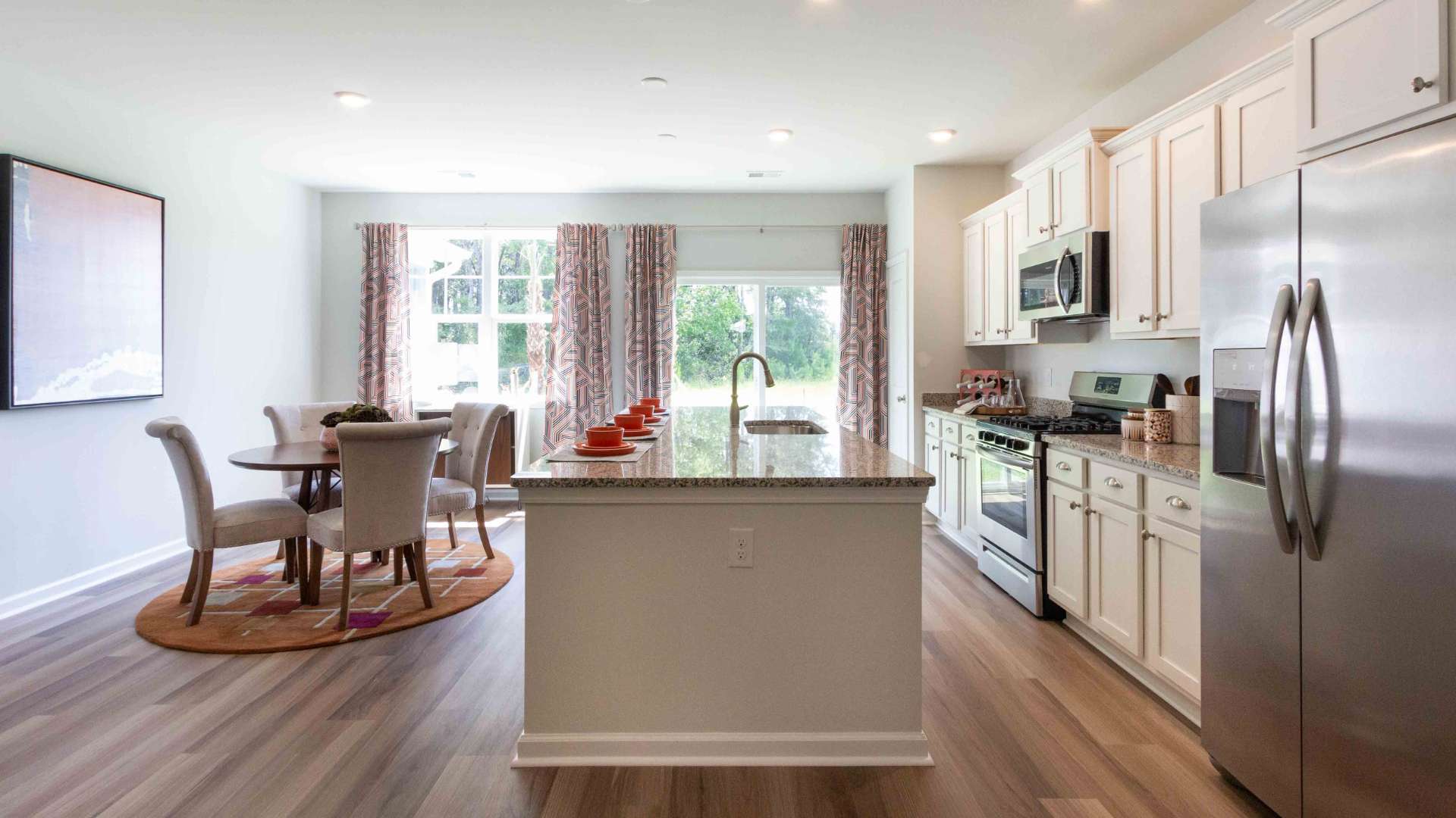 Large open concept Kitchen with a center island, stainless steel appliances, and dining area in the background.