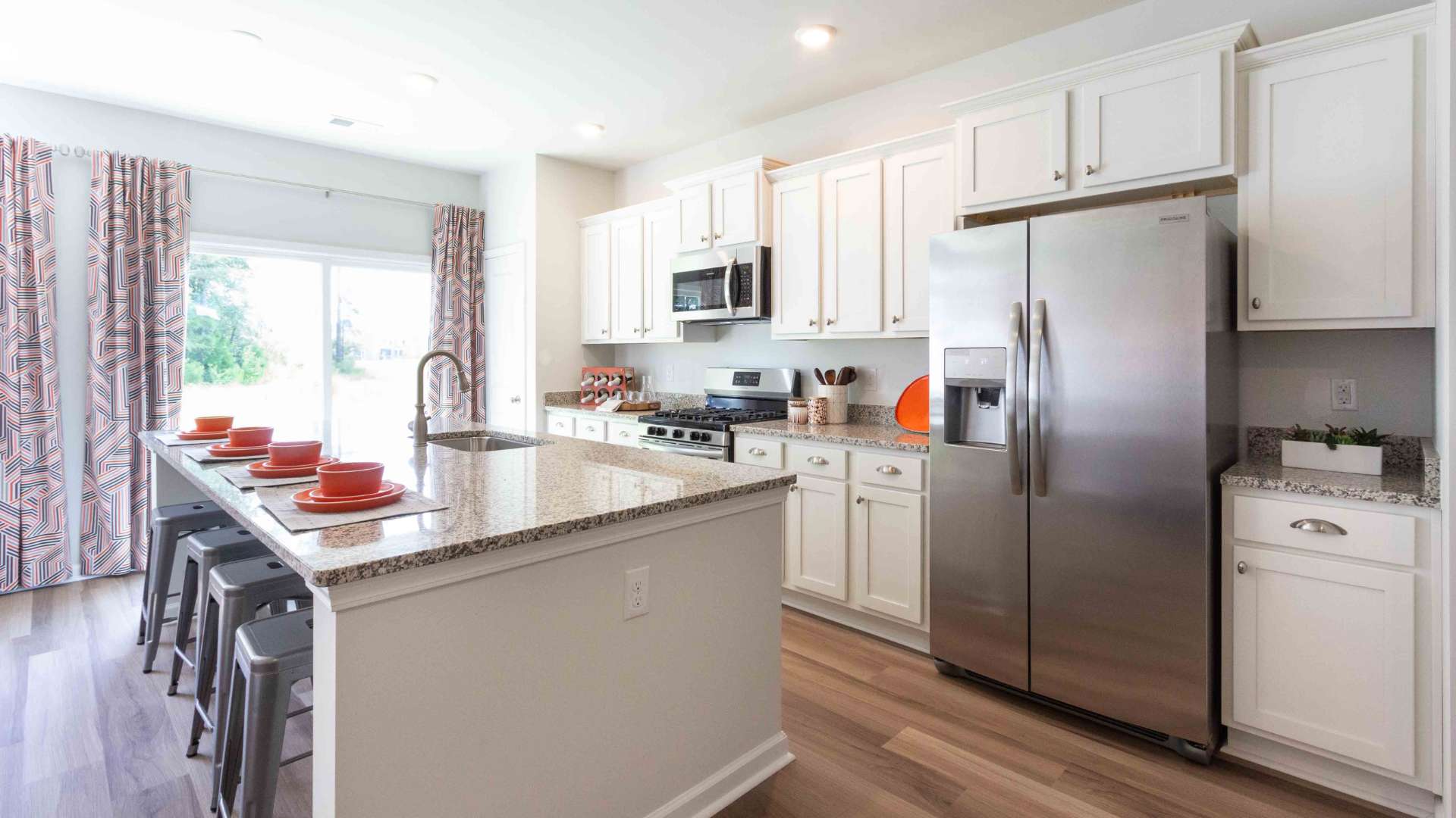 Kitchen from another angle, emphasizing cabinetry, island seating, and appliances