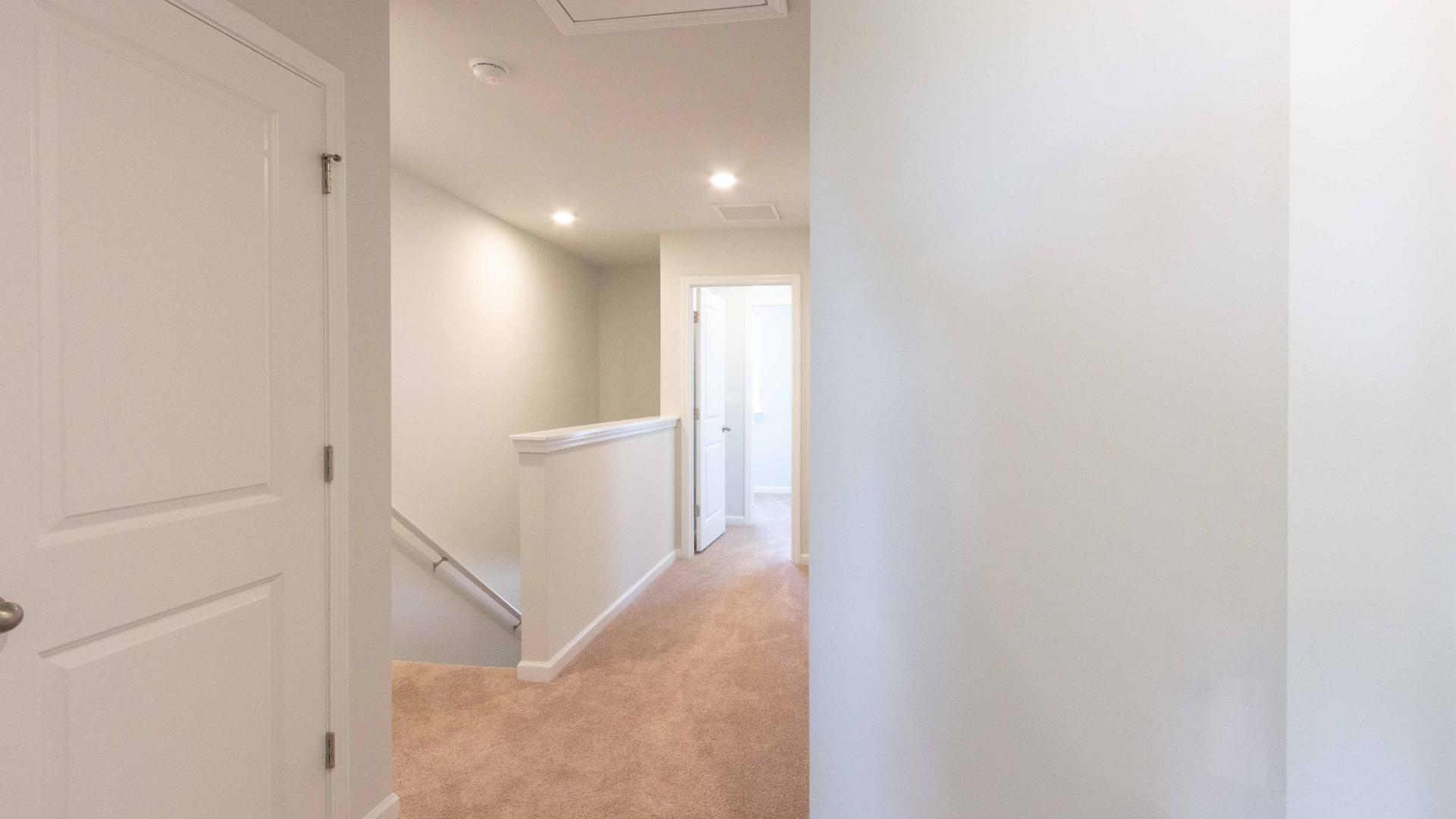 Upstairs hallway/landing space with carpeting and white walls