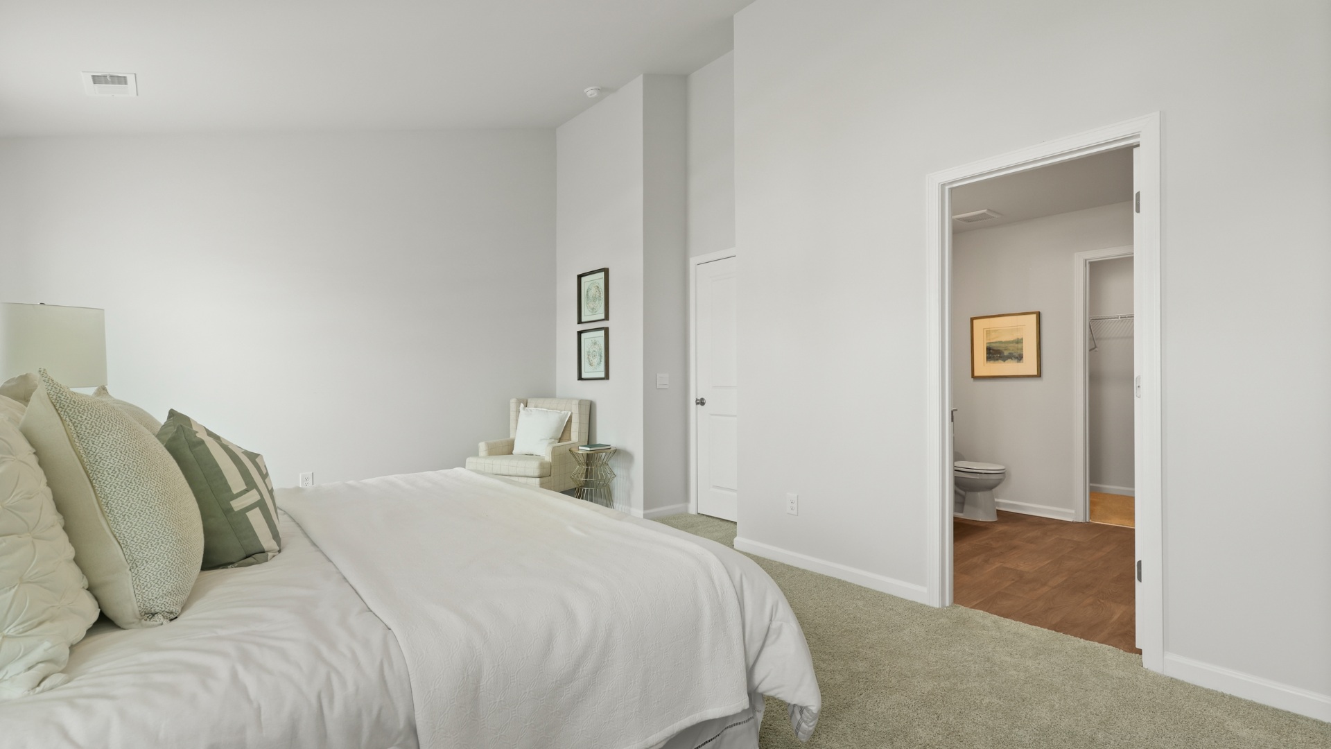 Primary bedroom decorated with a bed, side table and a sitting area
